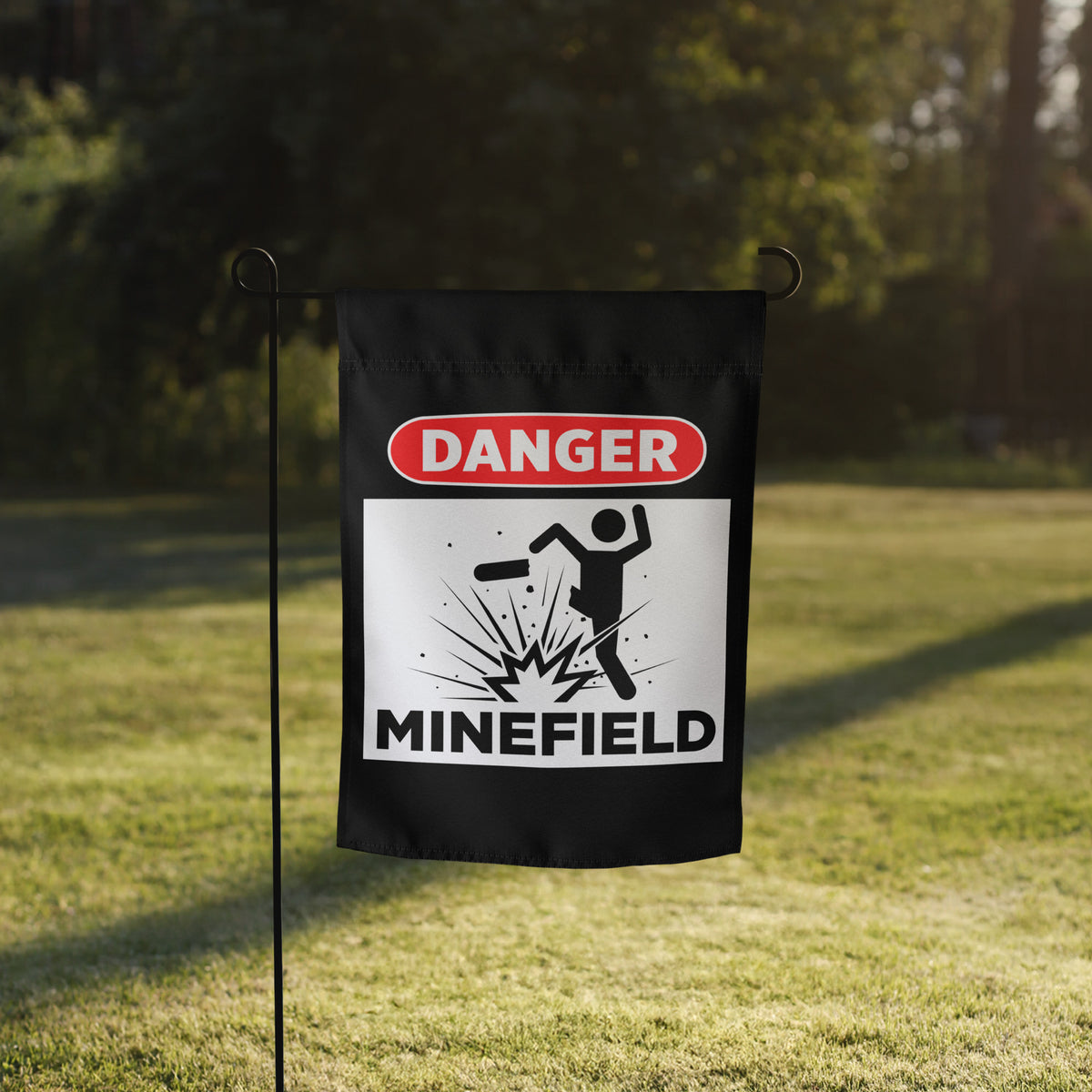 Garden flag with 'Danger Minefield' warning design on a grassy background