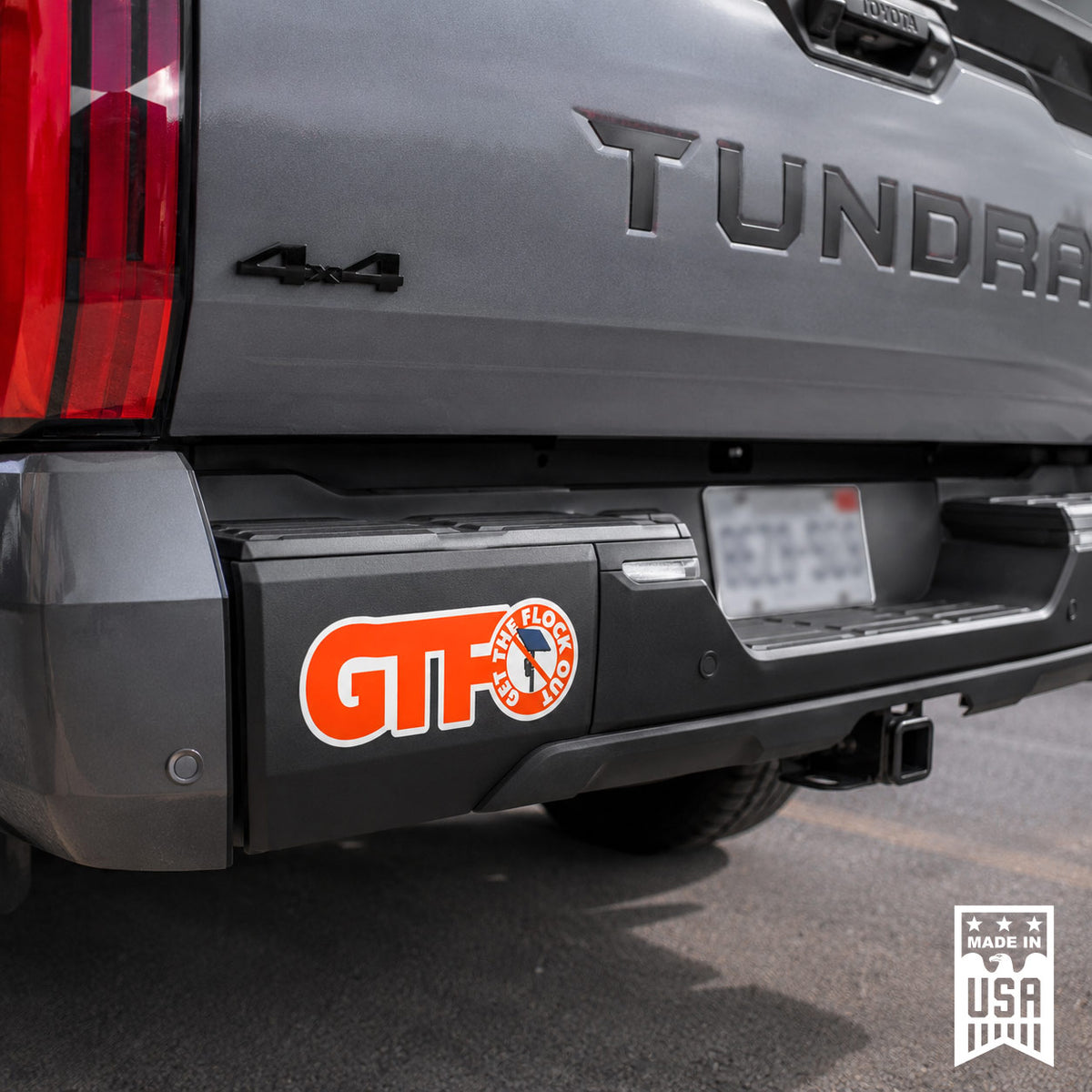 A close-up of the rear bumper of a gray Tundra truck, showing a red and orange 'Get the Flock Out' GTFO decal applied to the black bumper cover. A 'Made in USA' badge is visible in the bottom right corner.