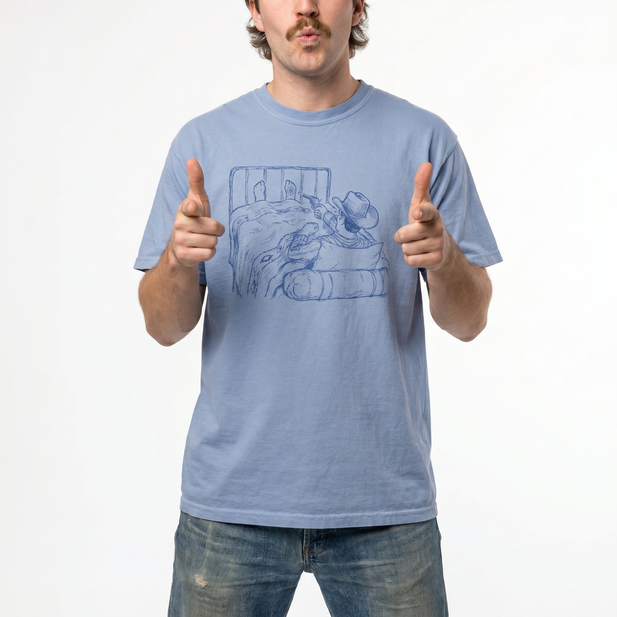Man wearing a light blue t-shirt with a graphic of a cowboy in bed shooting himself in the foot on a white background