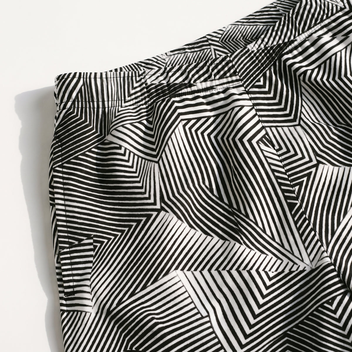 Black and white geometric striped fabric, likely a skirt or shorts, shown in a close-up with a visible waistband and side pocket on a white background.