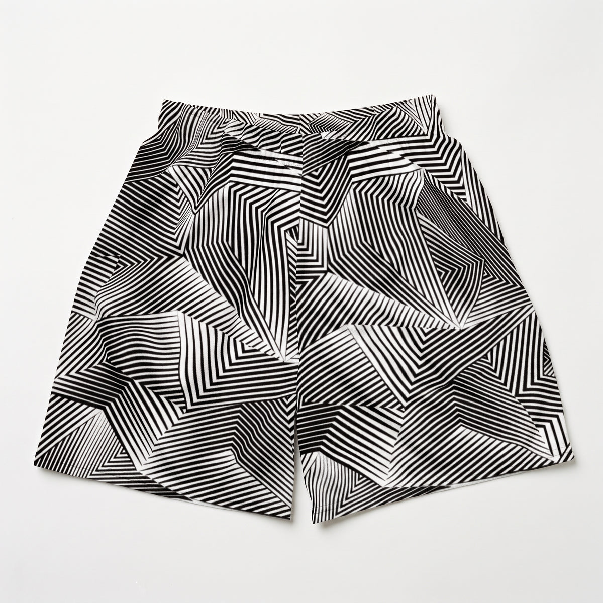 Black and white geometric patterned shorts with an abstract optical illusion stripe design, laid flat on a light gray background.