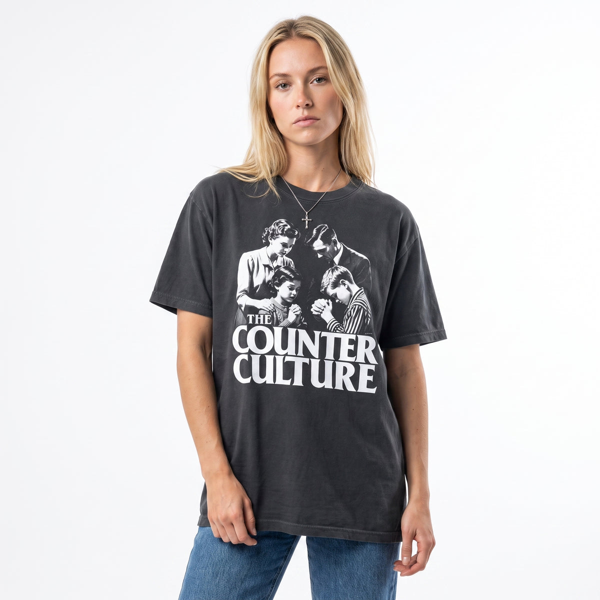 A woman modeling an oversized dark charcoal gray graphic t-shirt featuring a white print of the band 'The Counter Culture' with blue jeans, shot against a plain white background.