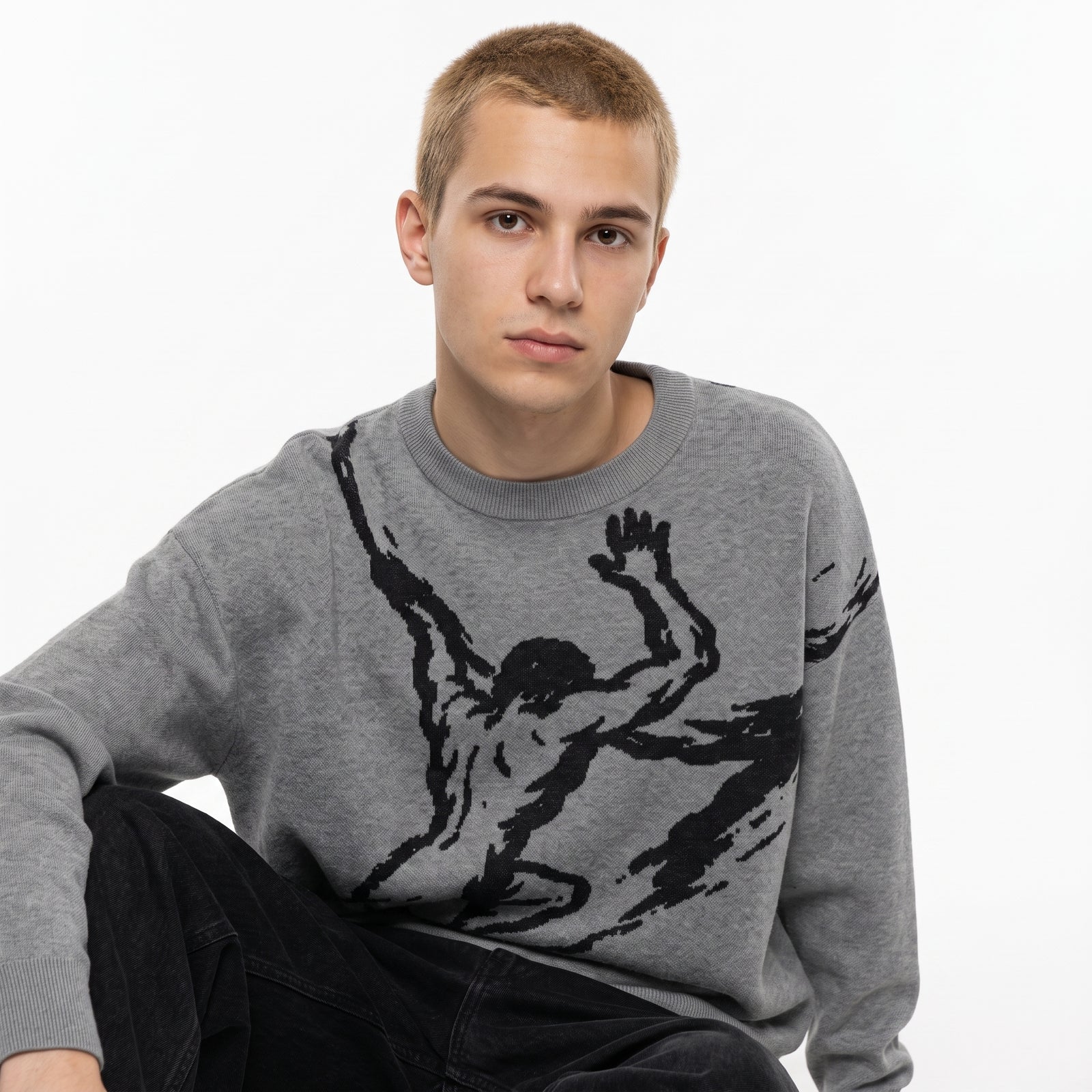 A young man wearing a gray crewneck sweater with a large black graphic print of a muscular figure, posed against a clean white background.