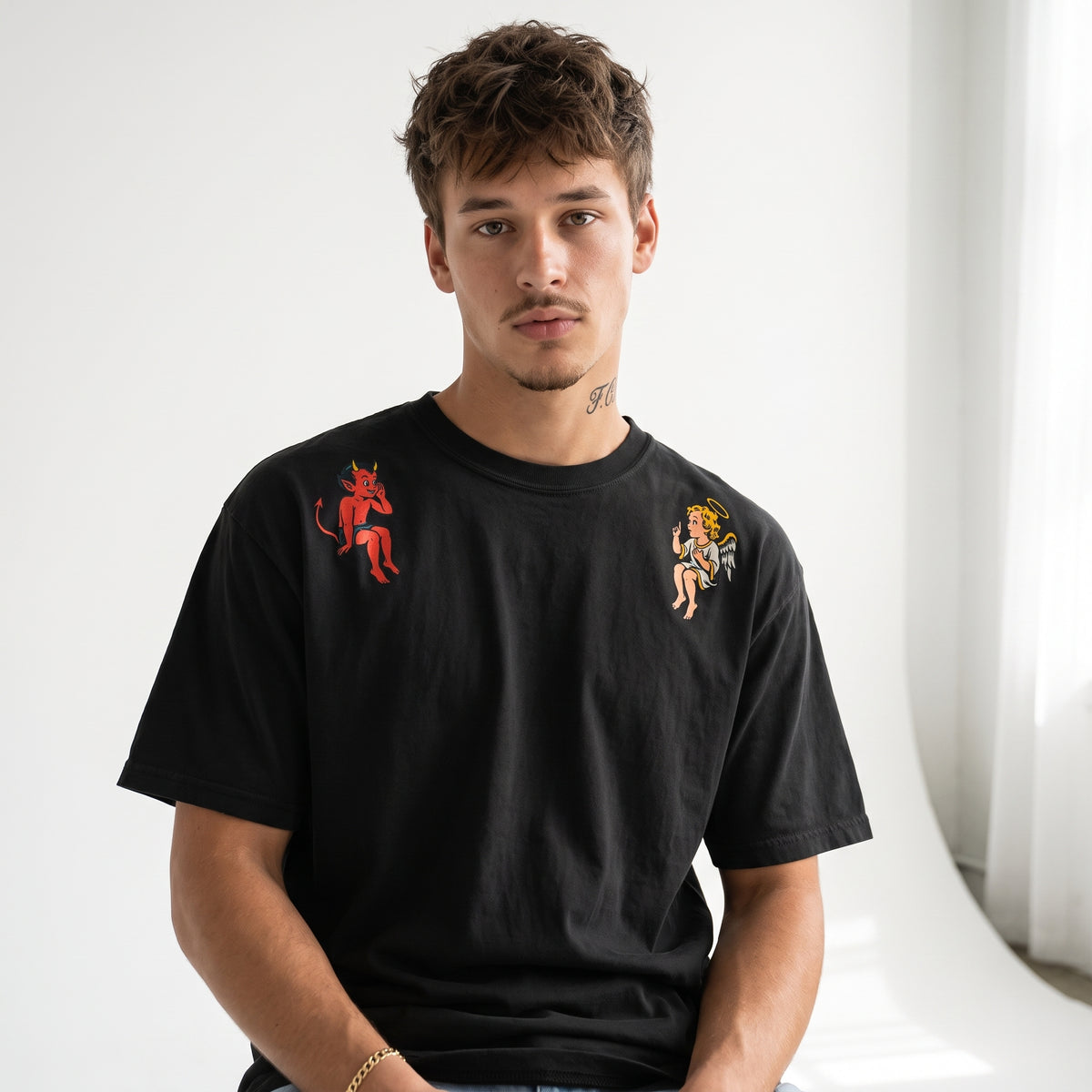 Male model wearing the black angel and devil shoulder graphic tee in a white studio