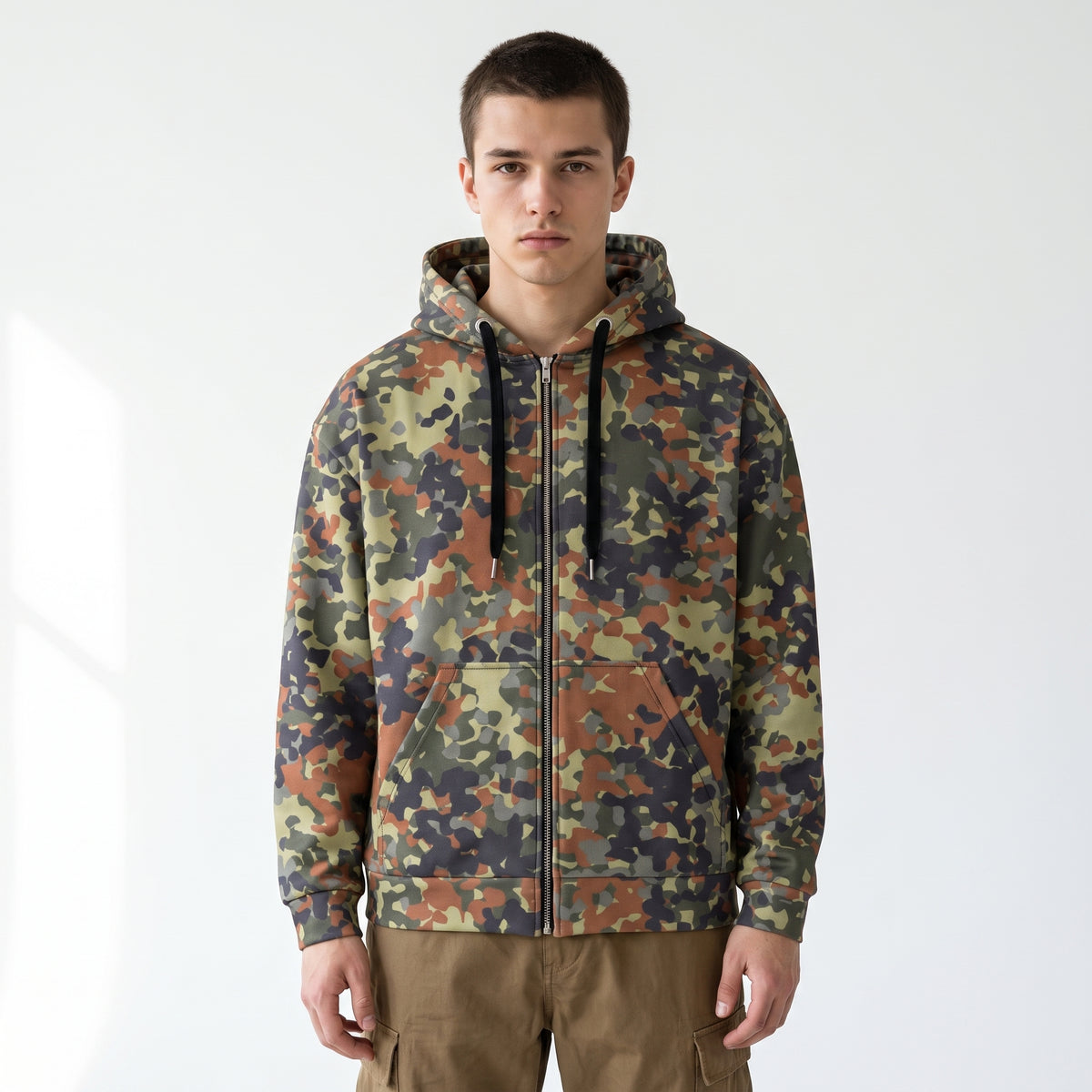 Man wearing the Flecktarn Reconnaissance camo zip hoodie in a white studio