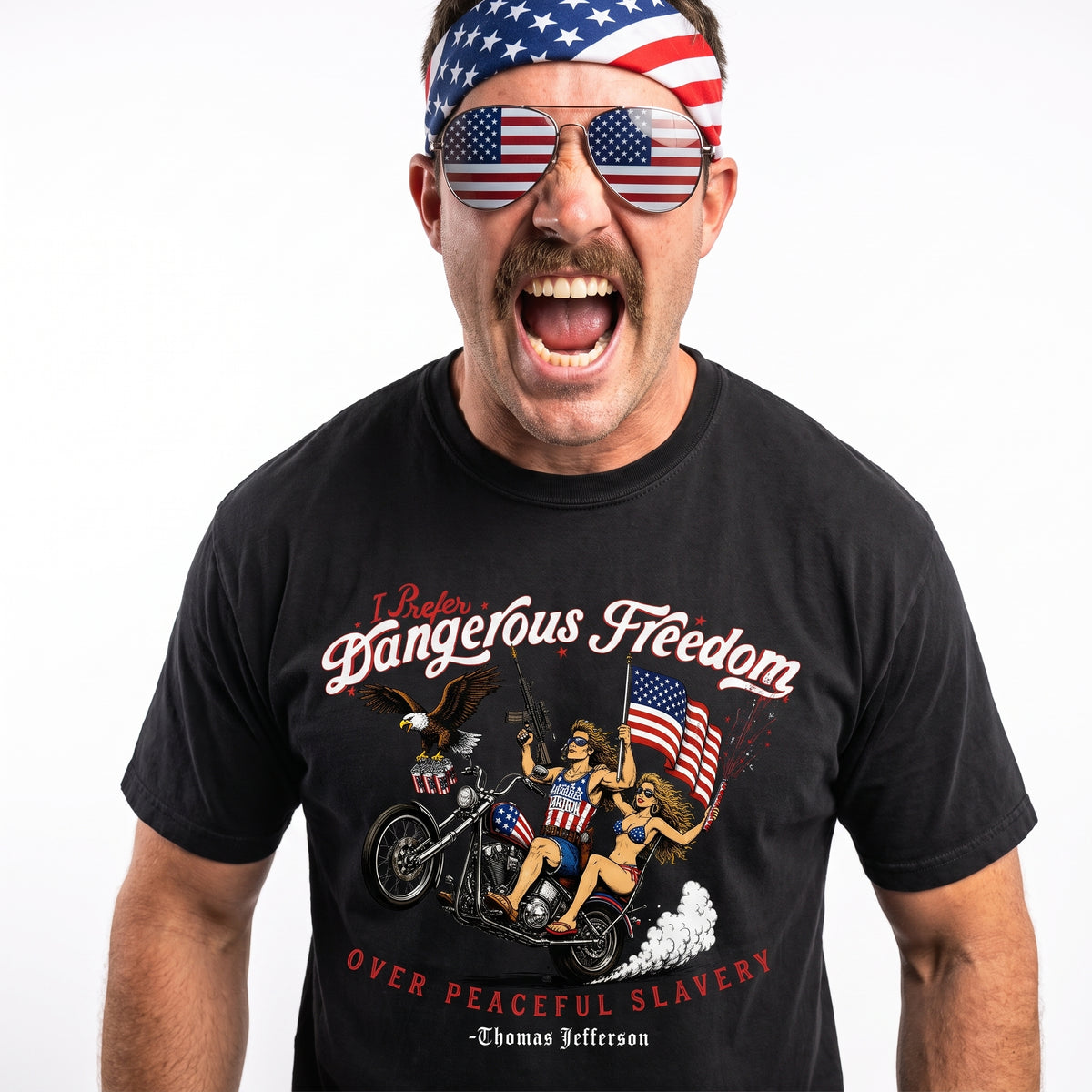 A man wearing a black graphic t-shirt with a patriotic design, matching American flag sunglasses, and an American flag headband, captured against a solid white background.