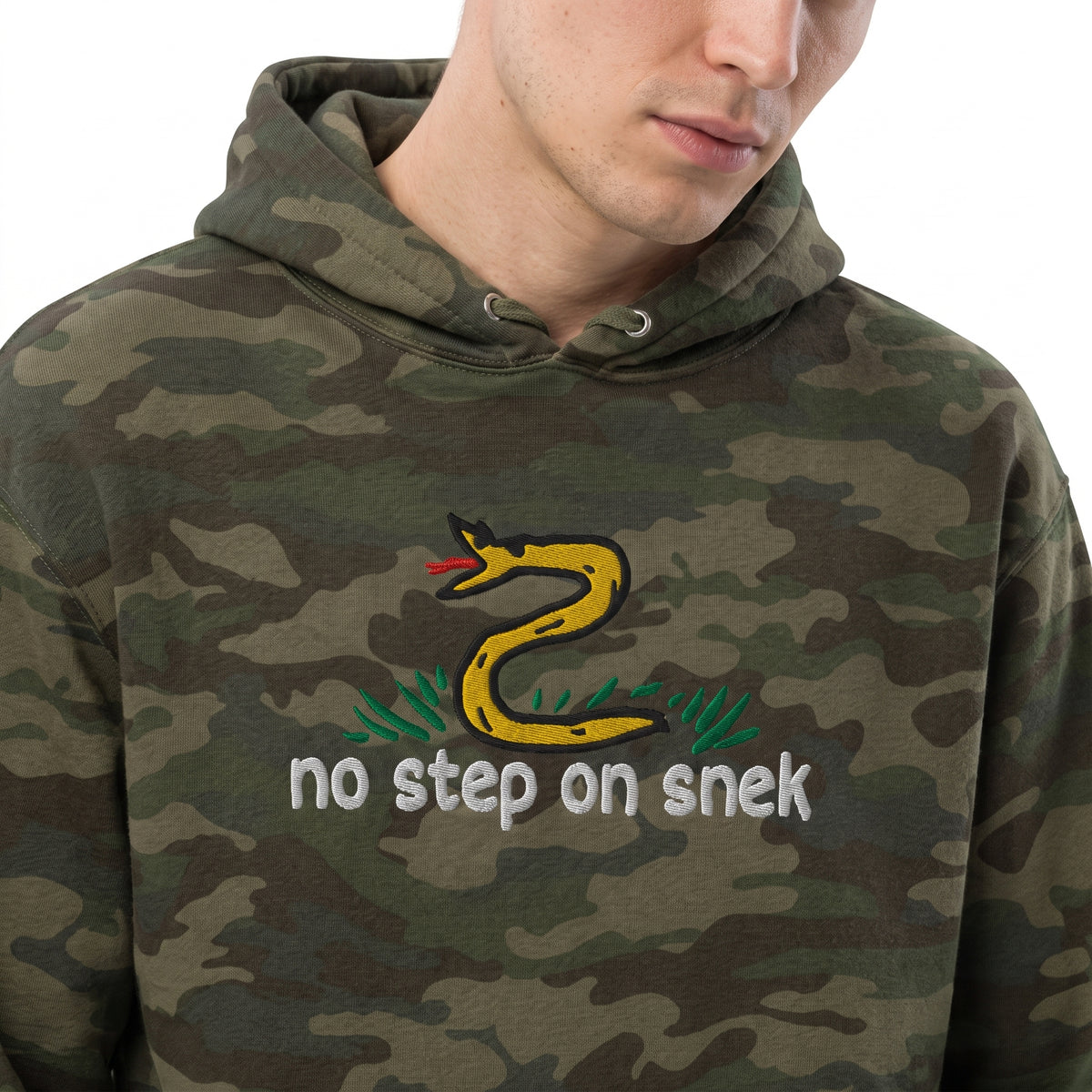 Man wearing Forest Camo No Step on Snek embroidered hoodie, chest close-up