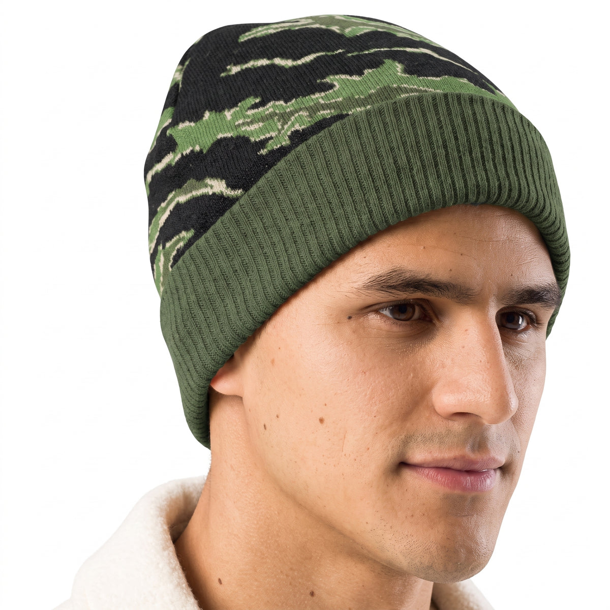A man wearing a knit beanie hat with a green and black tiger stripe pattern, shown in a close-up profile shot against a white background.