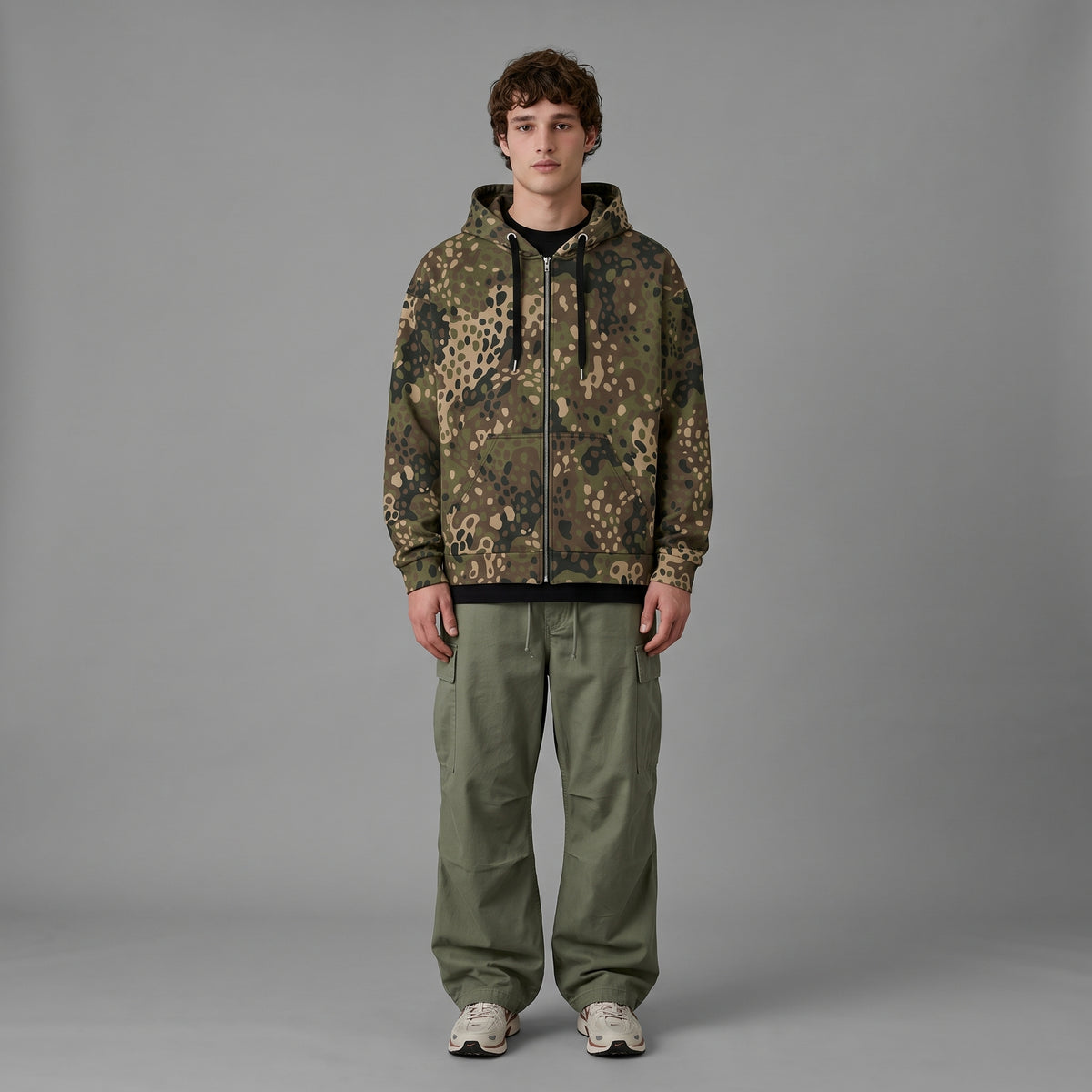 Man wearing the Erbsenmuster Pea Dot Field Green camo zip hoodie, full-length view