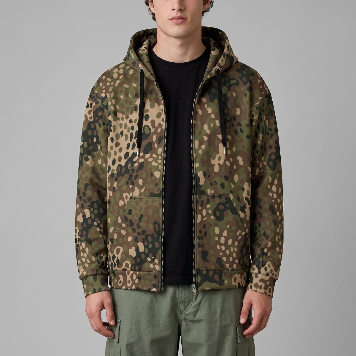 Man wearing the Erbsenmuster Pea Dot Field Green camo zip hoodie, by Liberty Maniacs