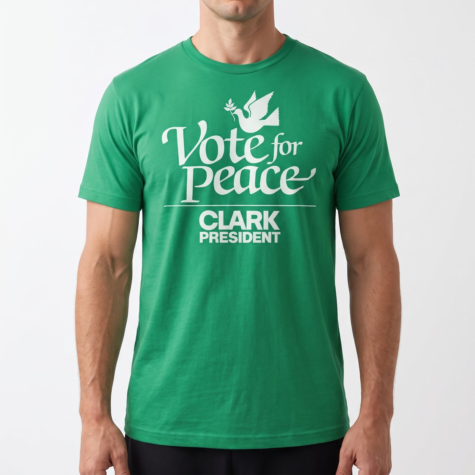 A man wearing a green crewneck t-shirt with a white graphic print that reads 'Vote for Peace CLARK PRESIDENT' with a dove illustration, shown against a plain light gray background.