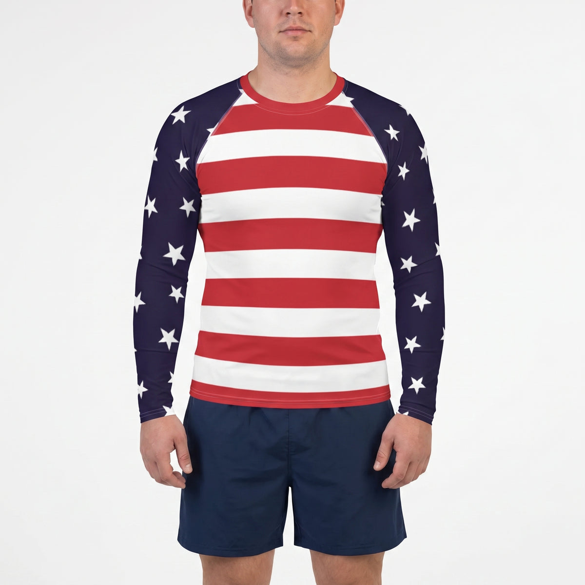 A man wearing a long-sleeve raglan shirt with an American flag pattern, featuring red and white horizontal stripes on the front and navy blue sleeves with white stars, paired with navy blue shorts, against a plain white background.