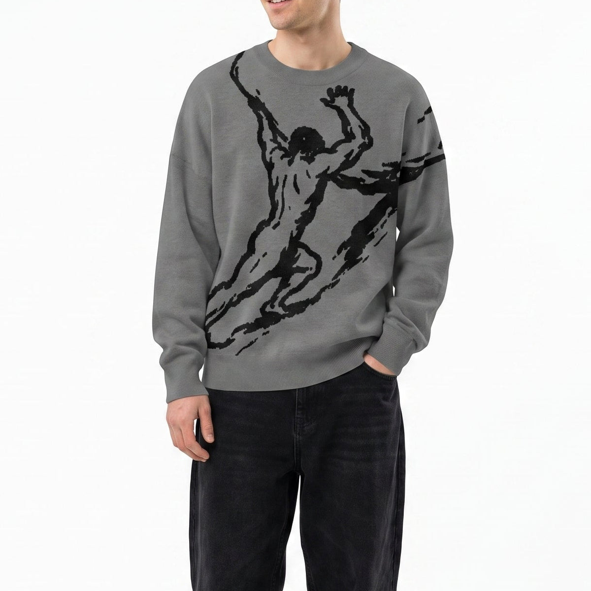 A man wearing a gray crewneck sweatshirt with a black graphic print of a running figure, paired with black jeans and black sneakers, standing against a plain white background.