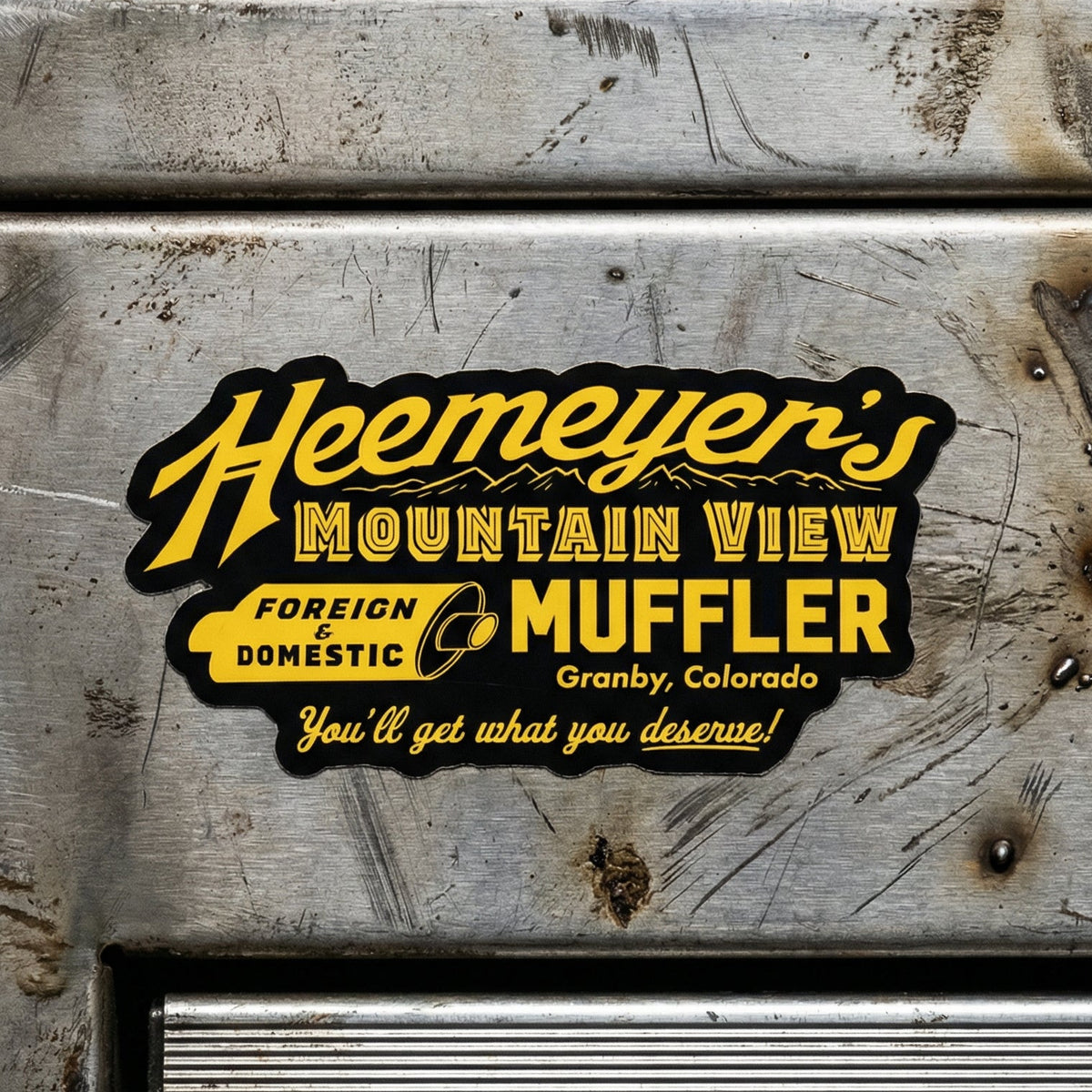 Metal surface with a 'Heemeyer's Mountain View Muffler' logo and text.