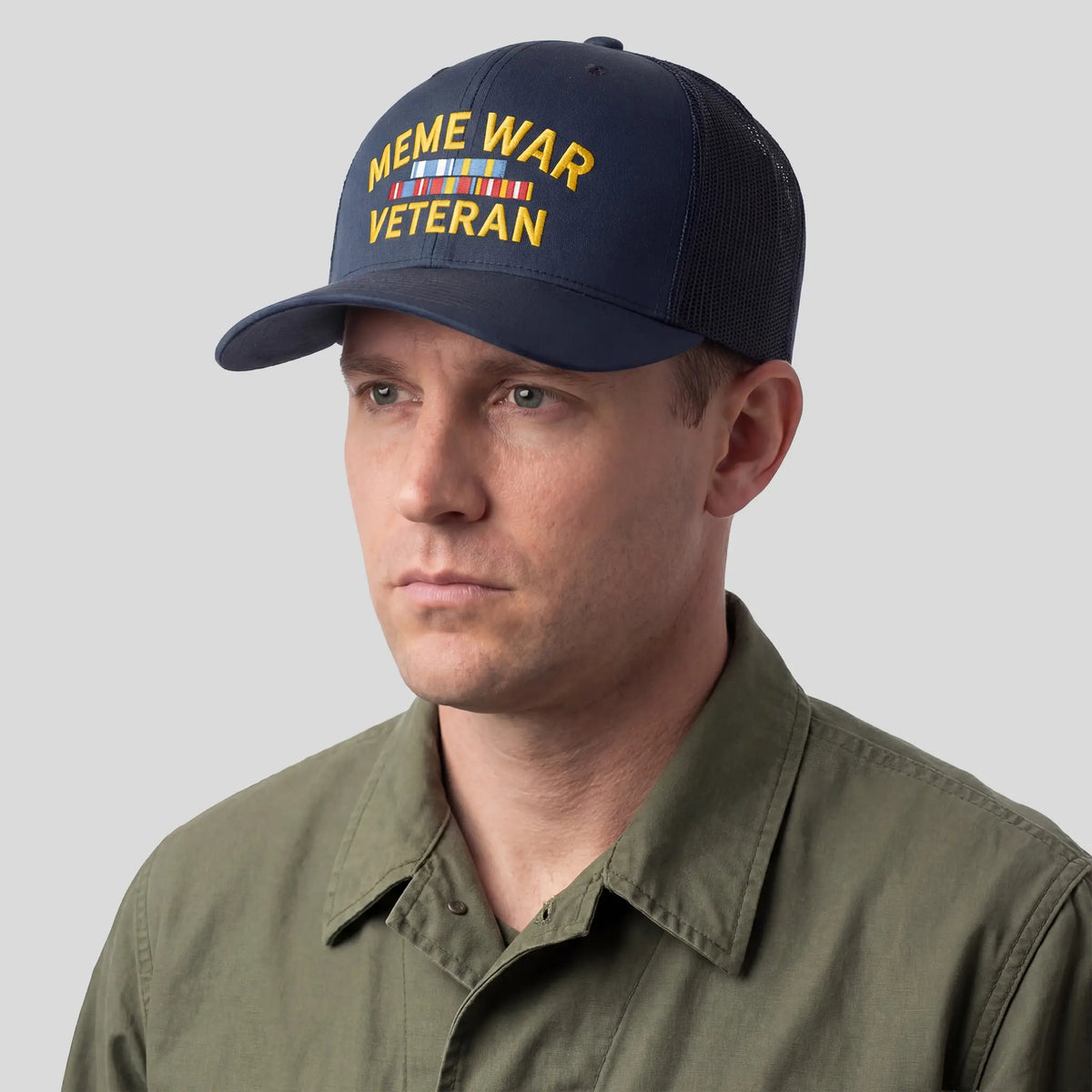 Man wearing a navy cap with 'Meme War Veteran' text on a plain background