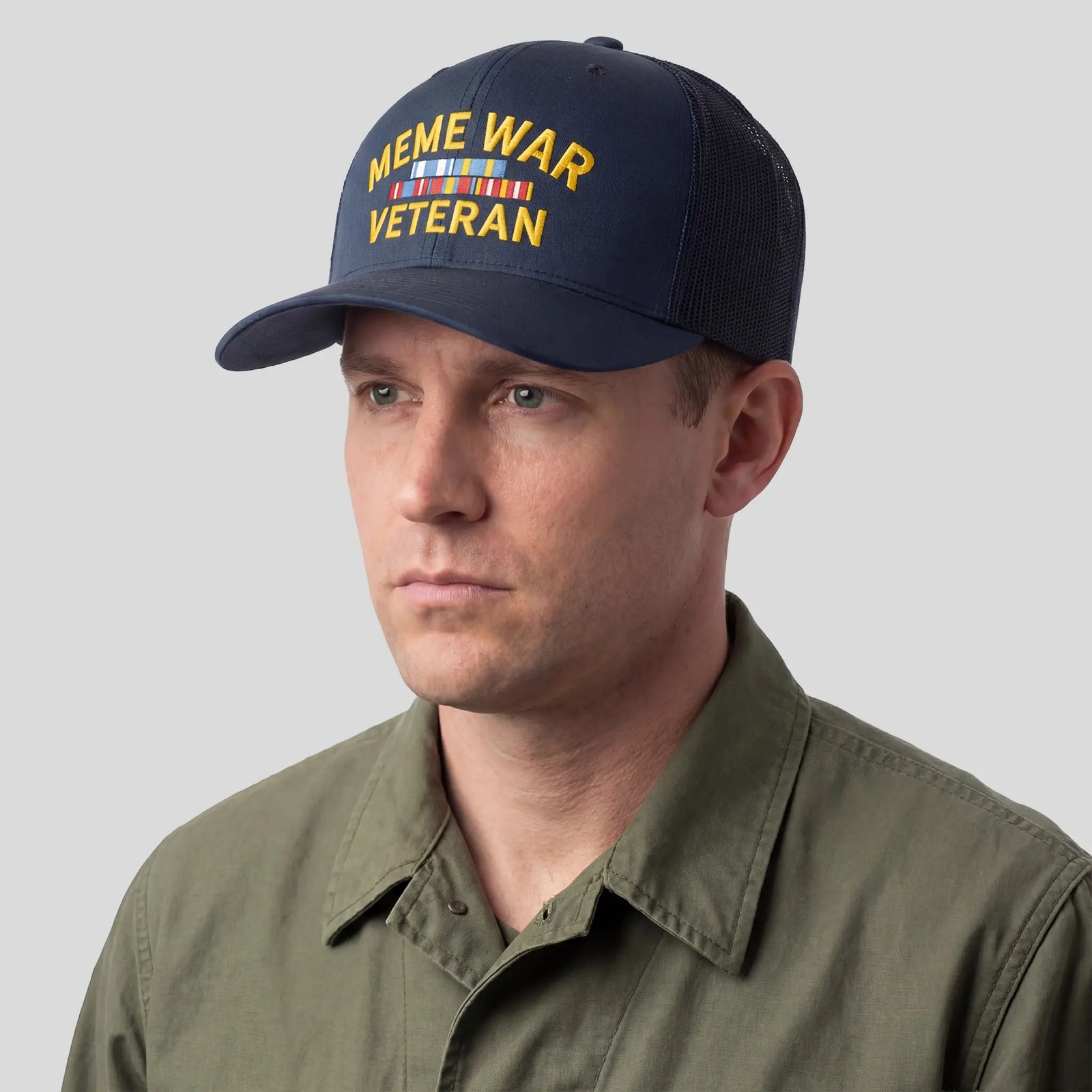 A navy blue six-panel trucker cap with a mesh back featuring the text 'MEME WAR VETERAN' in bold letters on the front.