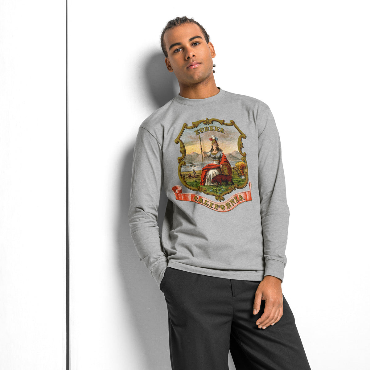 Man leaning against a wall in the Carbon Grey vintage California State Seal long sleeve T-shirt and black pants.