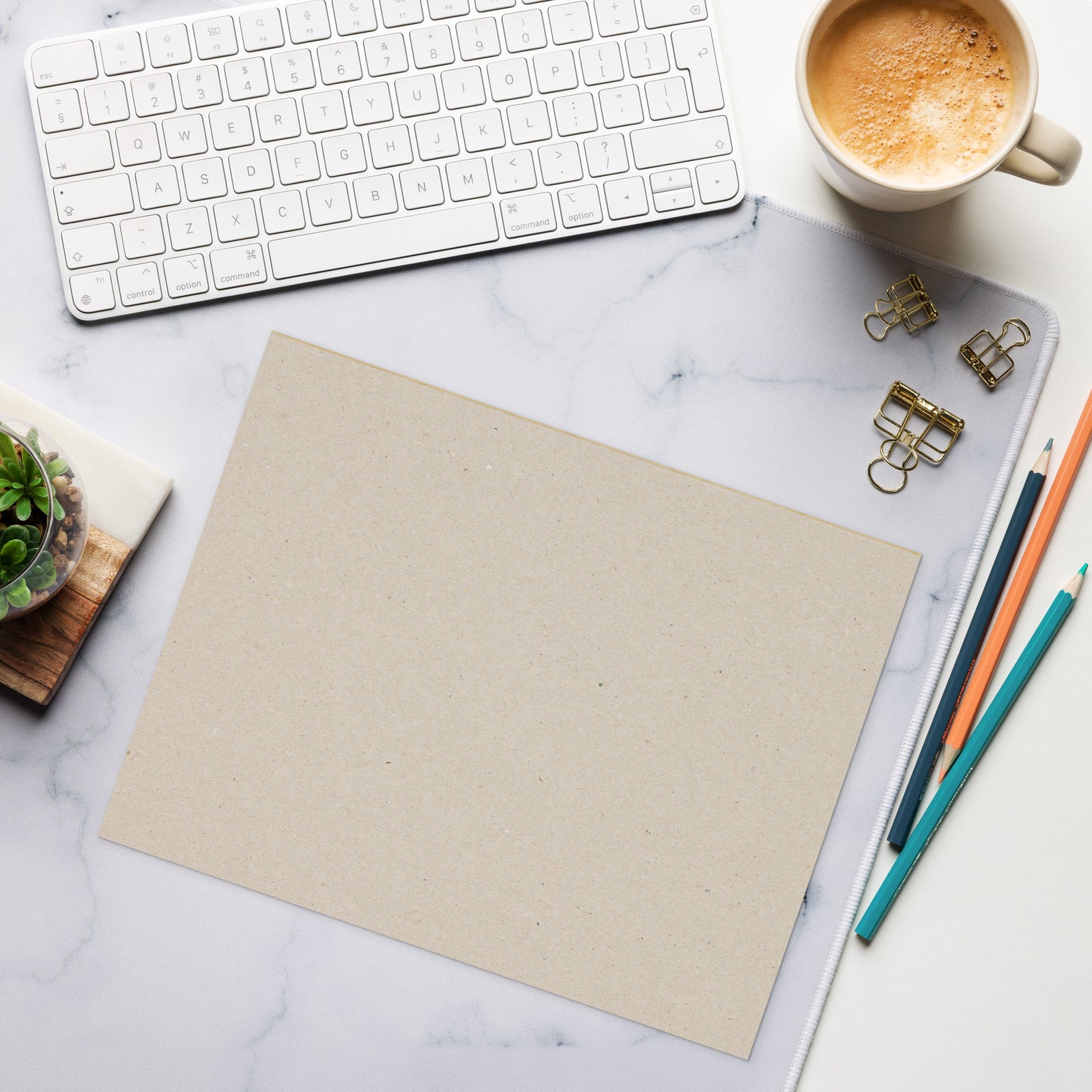 Desk setup with keyboard, coffee, paper, and office supplies on a marble surface