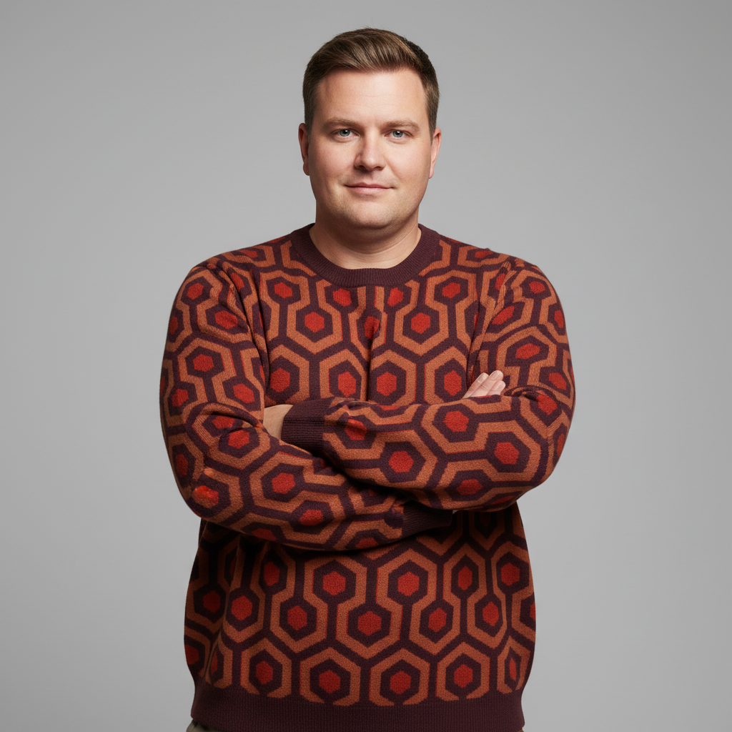 Man wearing a patterned sweater with a geometric design on a gray background