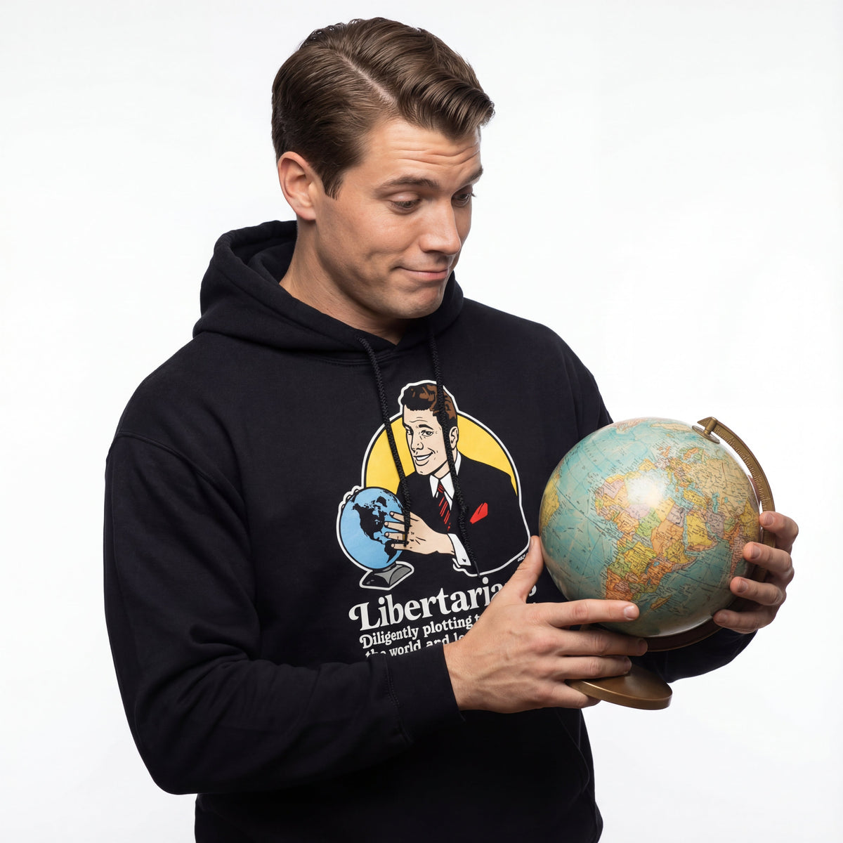 Man wearing a black hoodie with a graphic design holding a globe on a white background