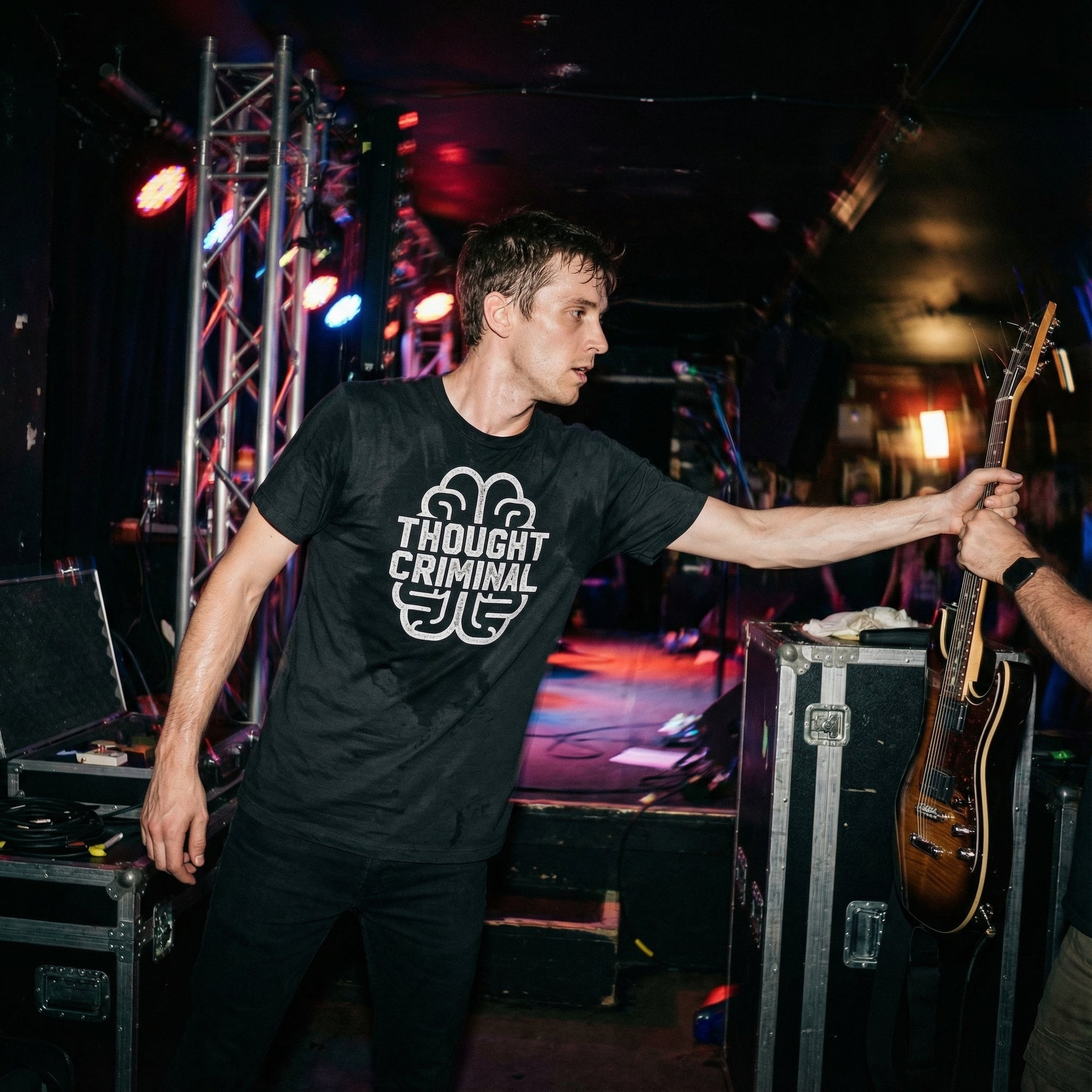 Man wearing a black t-shirt with 'Thought Criminal' graphic design on a plain background