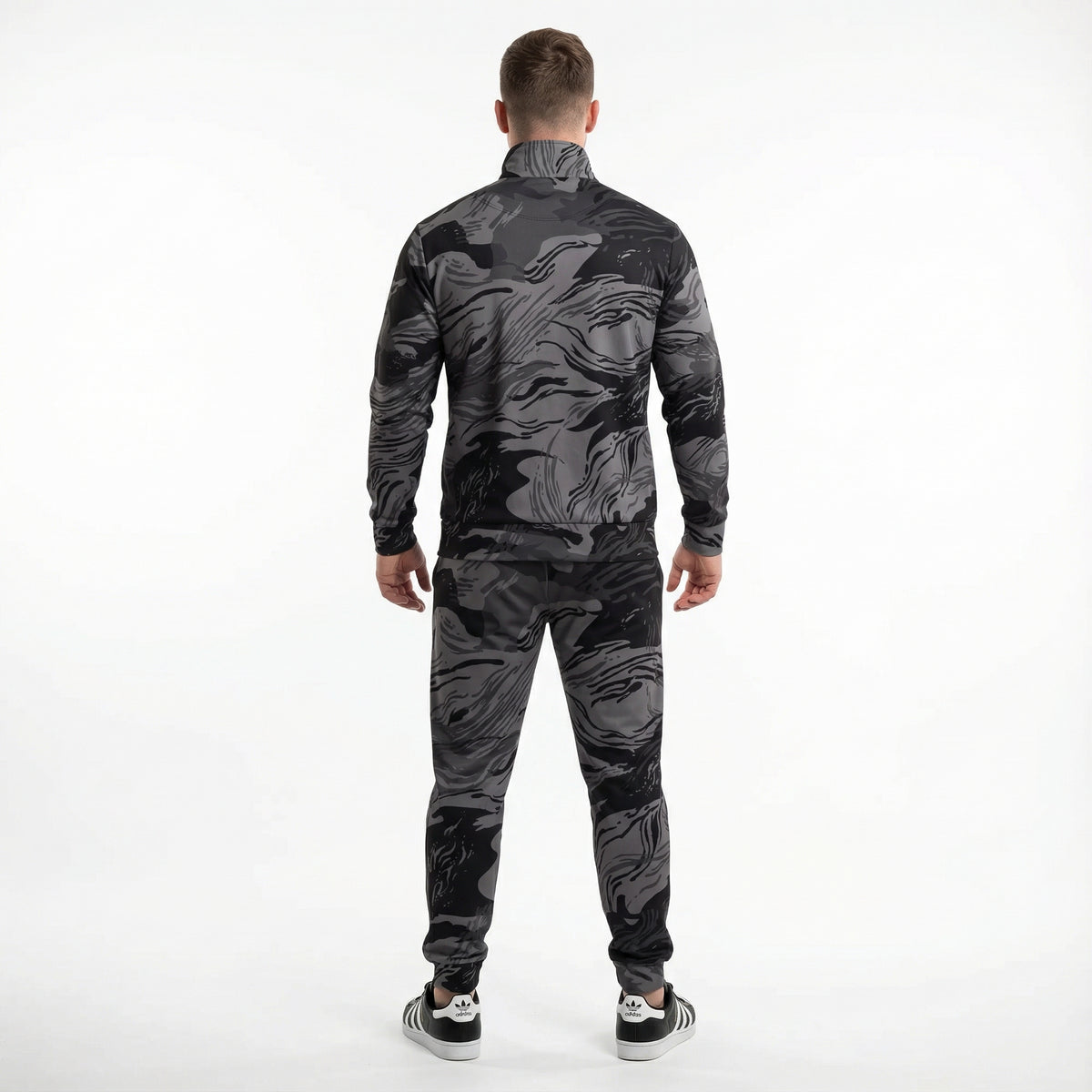 Man wearing a black and gray camouflage tracksuit on a white background