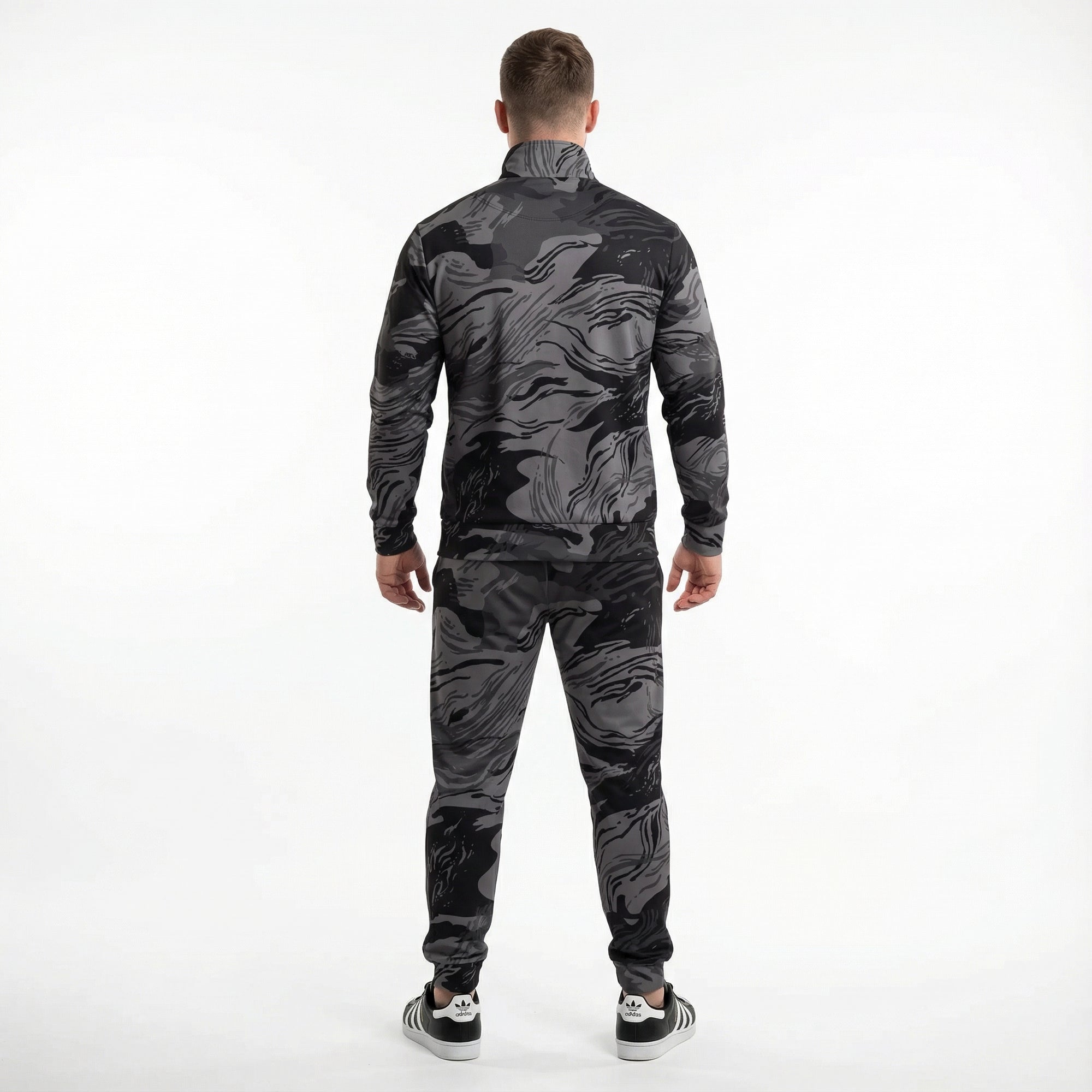 Man wearing a black and gray camouflage tracksuit on a white background