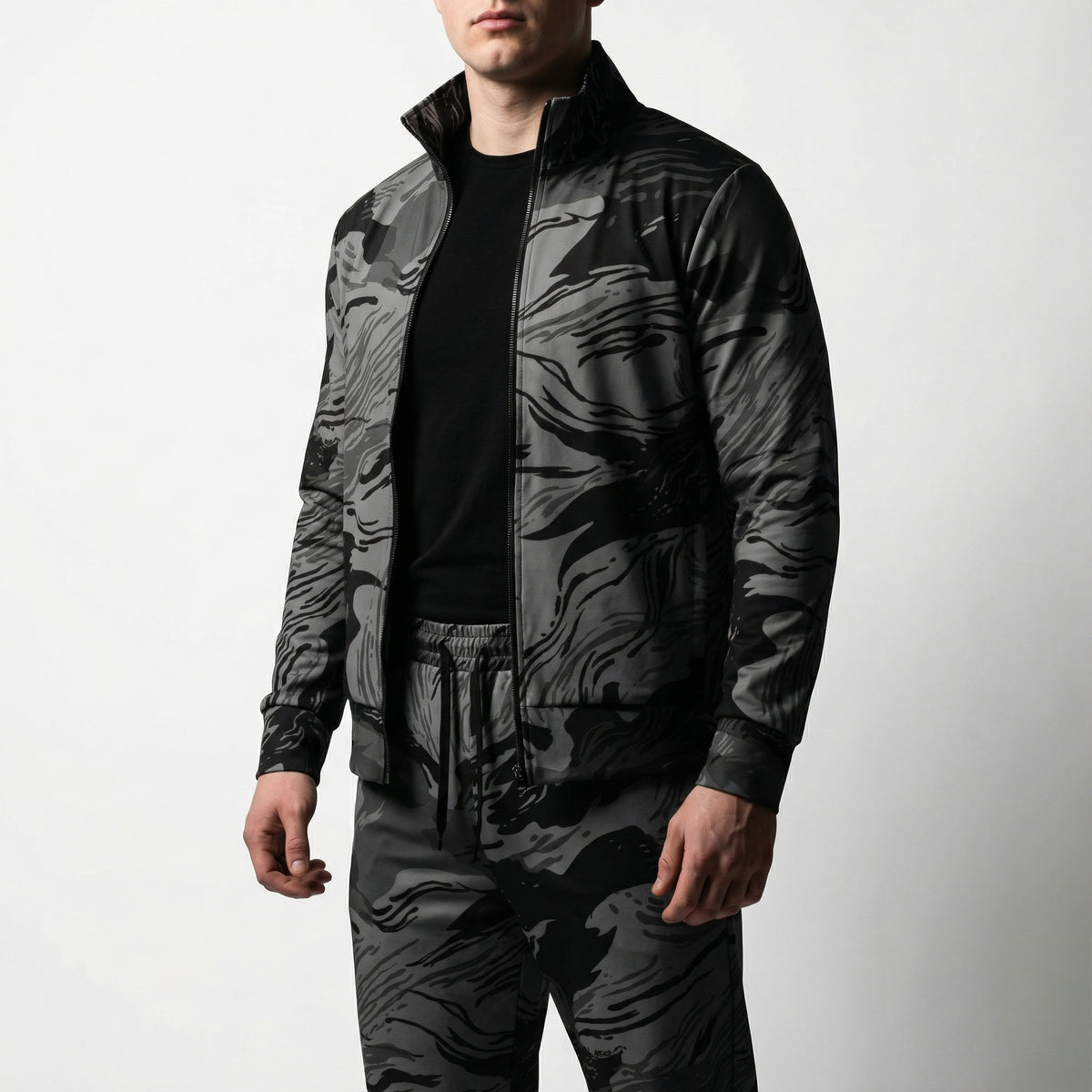 Person wearing a black and gray camouflage jacket and pants on a white background