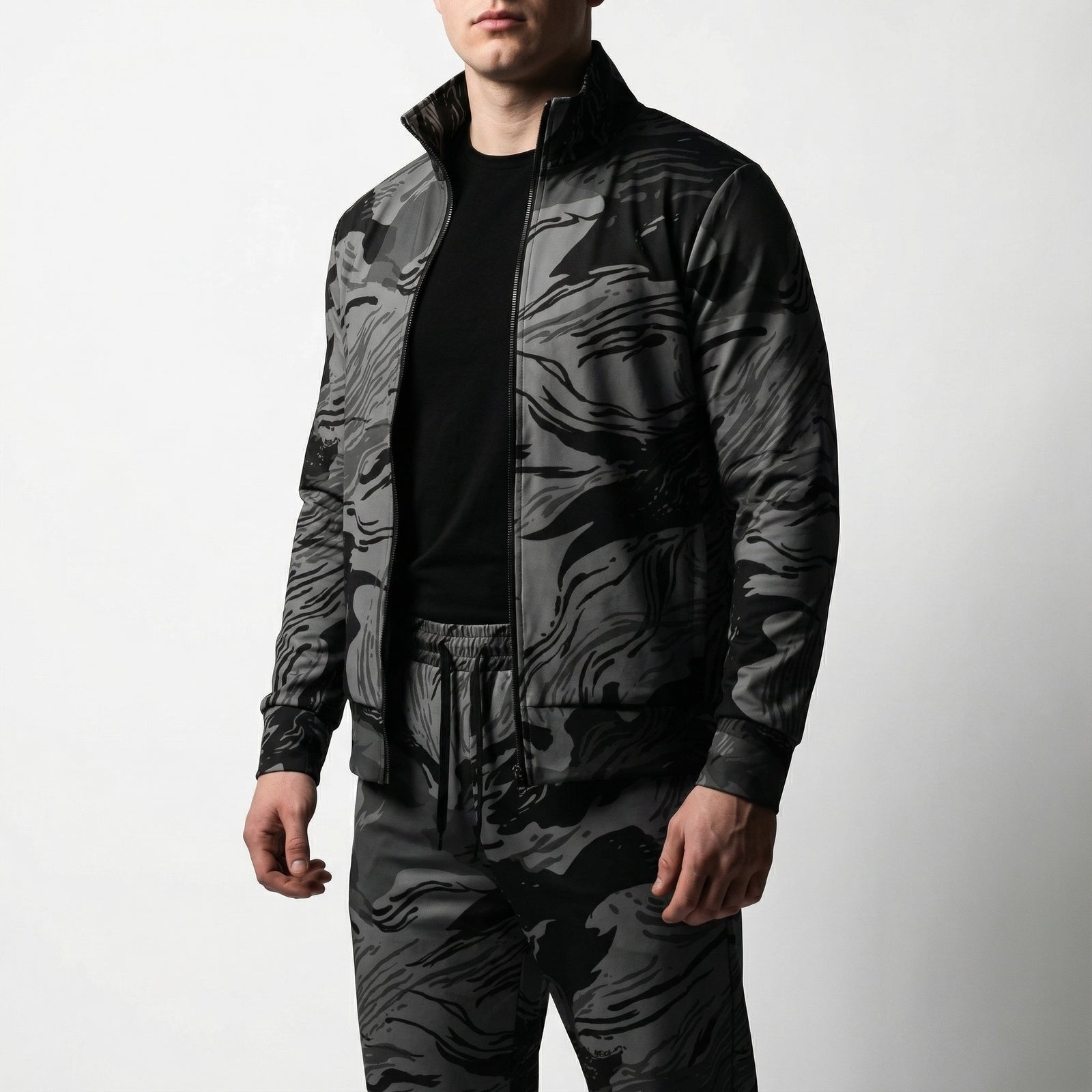 Person wearing a black and gray camouflage jacket and pants on a white background