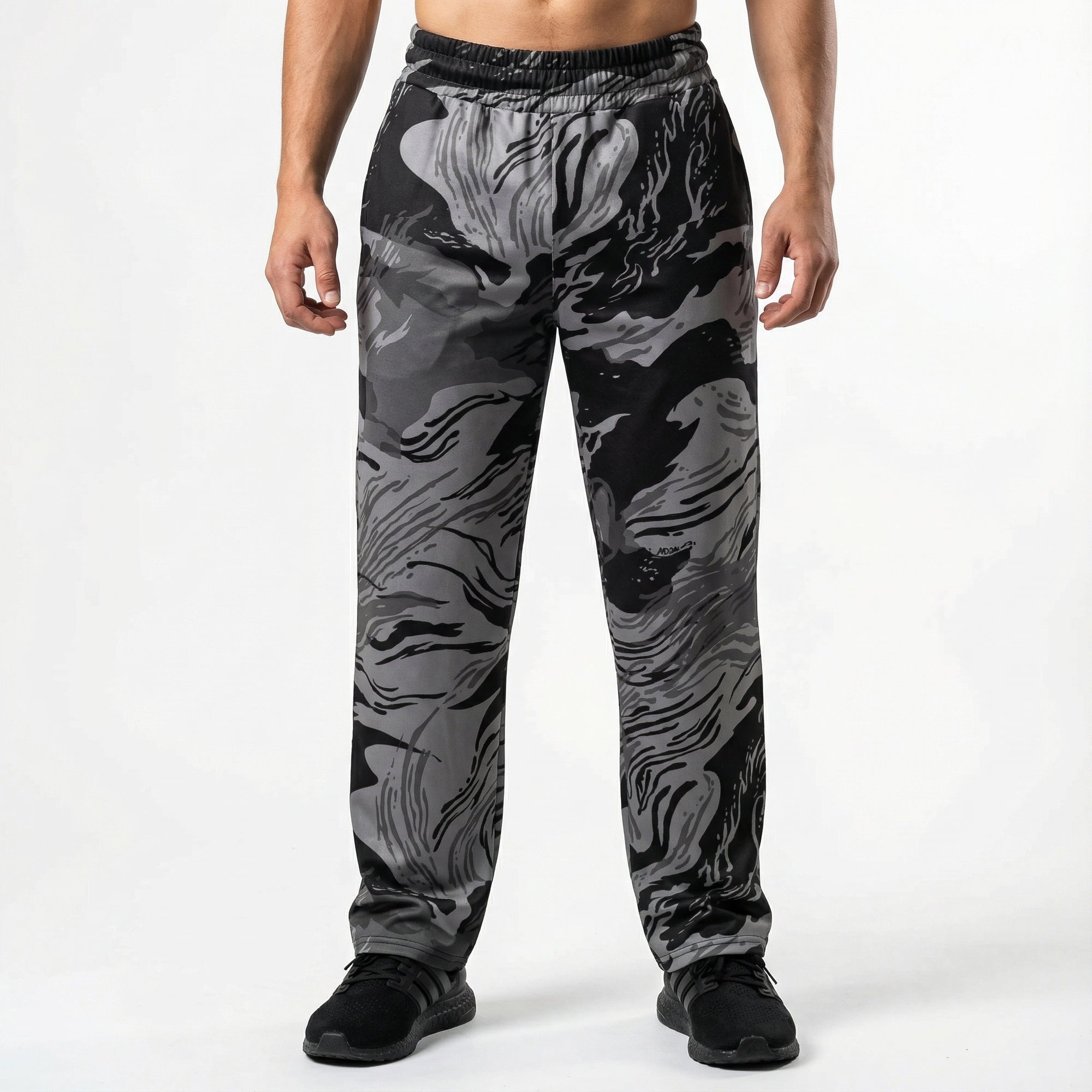 Person wearing black and gray camouflage pants on a white background