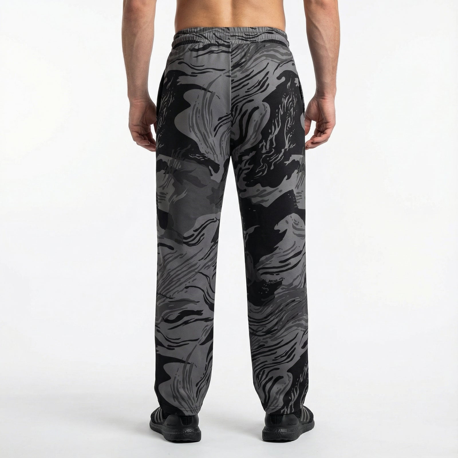 Person wearing black and gray camouflage pants on a white background
