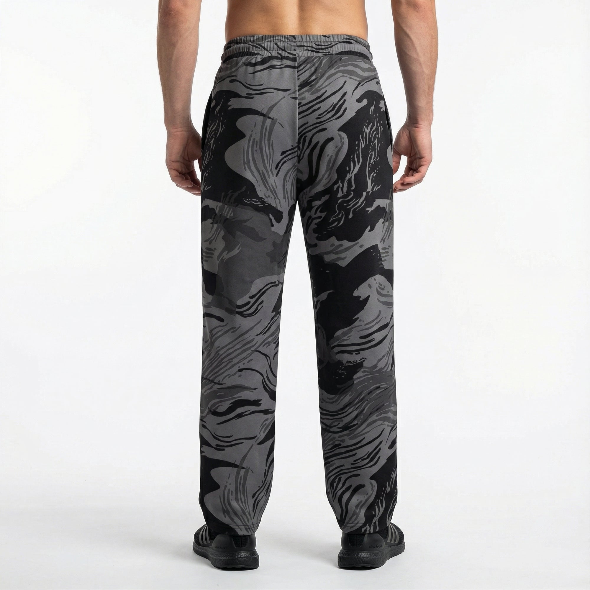 Person wearing black and gray camouflage pants on a white background