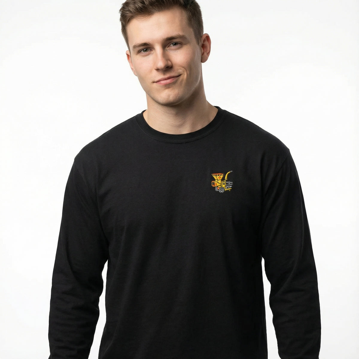 Man wearing a black long-sleeve shirt with a woodchipper embroidered on the front chest on a white background