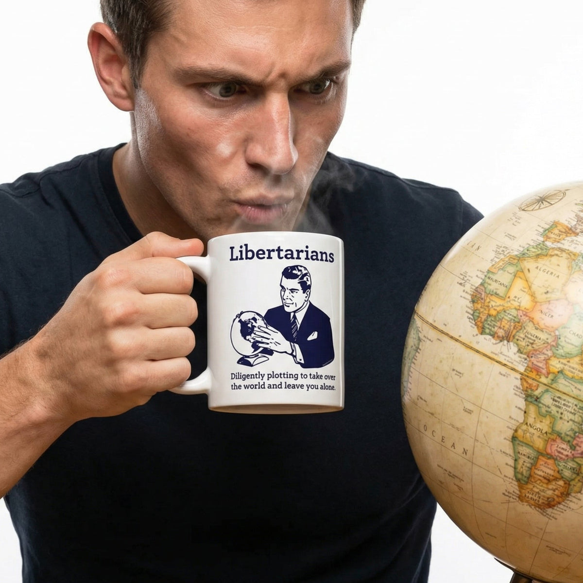 Man holding a mug with a political message next to a world globe on a white background