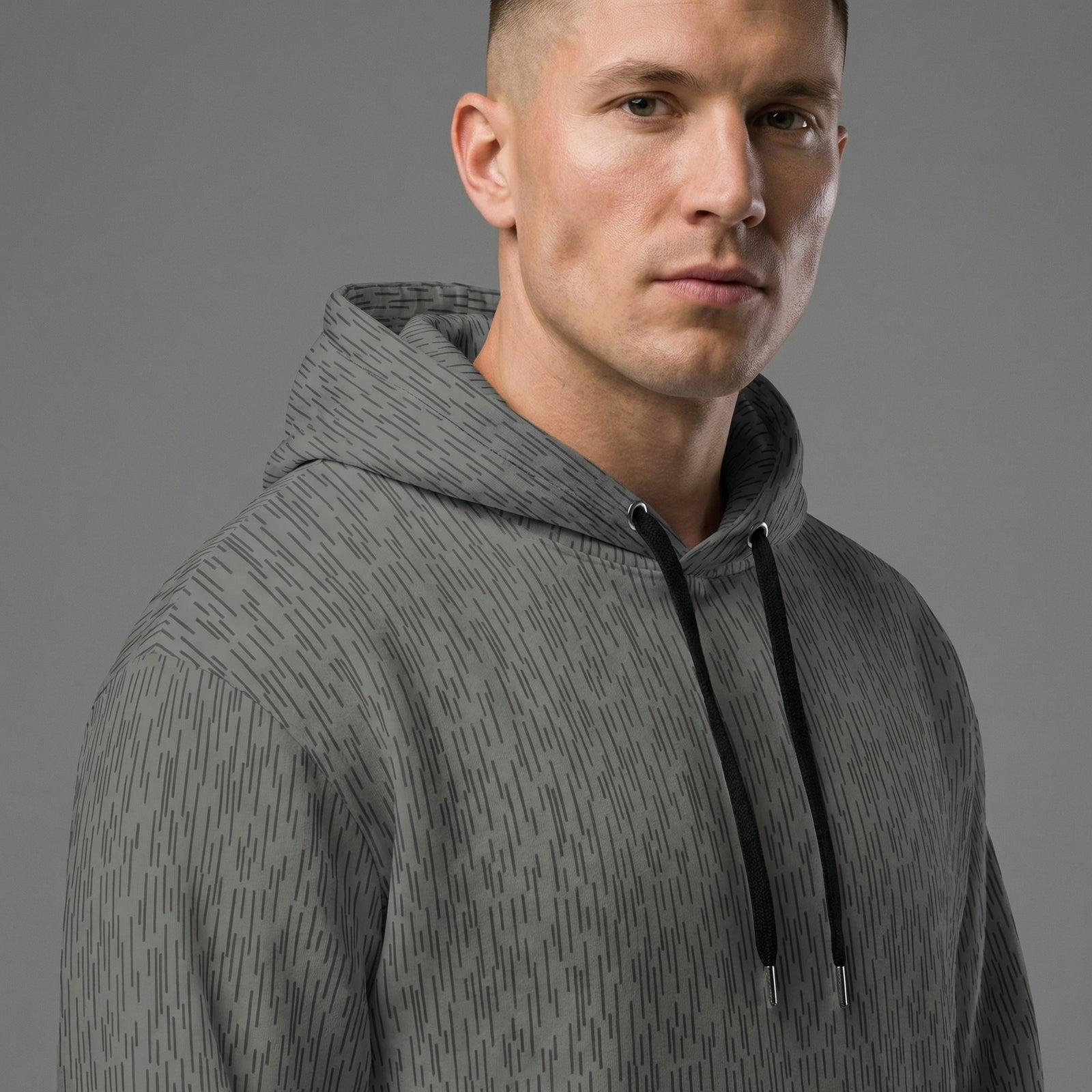 Man wearing a gray hoodie with a subtle pattern on a gray background