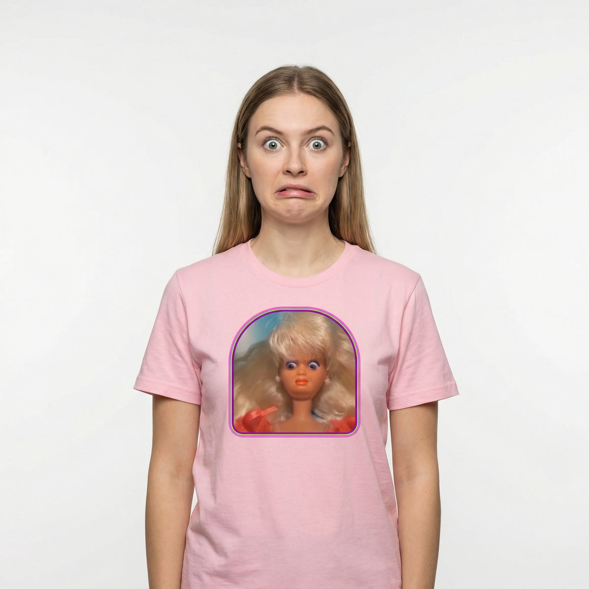 Person wearing a pink t-shirt with a graphic of a doll on a white background