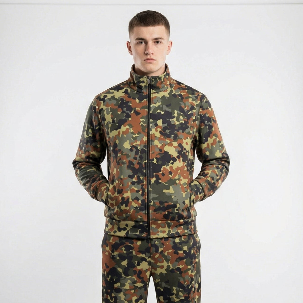Man wearing a camouflage tracksuit standing in front of studio lights on a white background