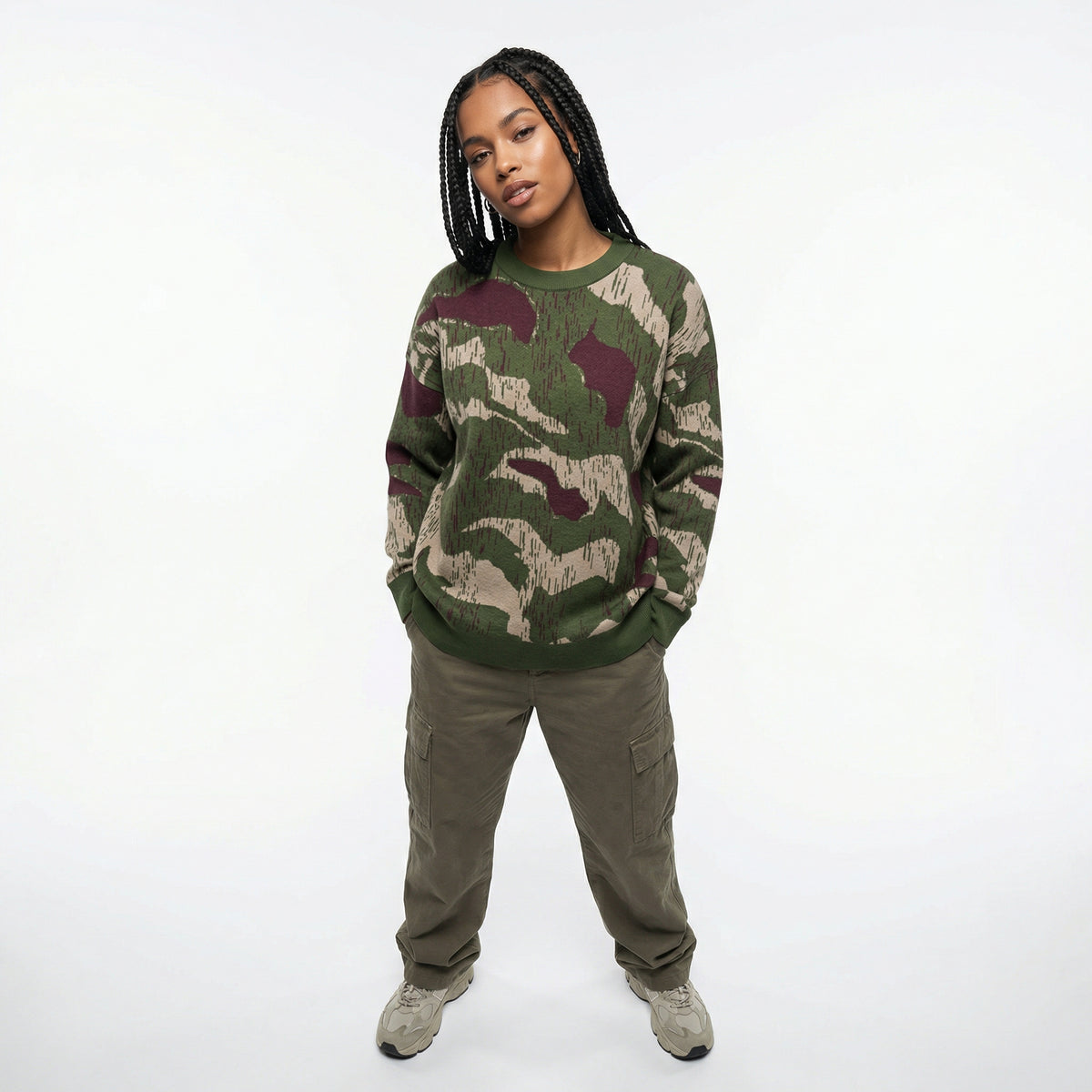 Person wearing a camouflage sweater and cargo pants on a white background