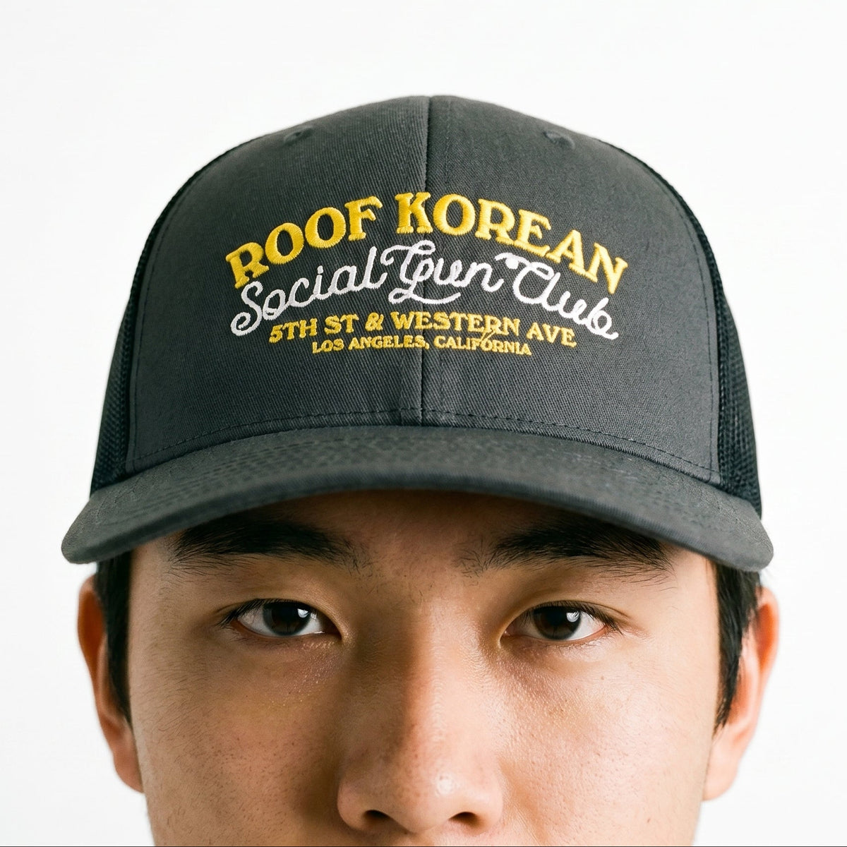 Black cap with yellow text worn by a person on a white background