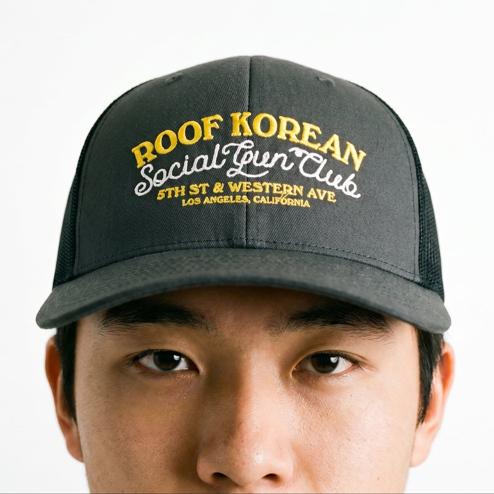 Black cap with yellow text worn by a person on a white background