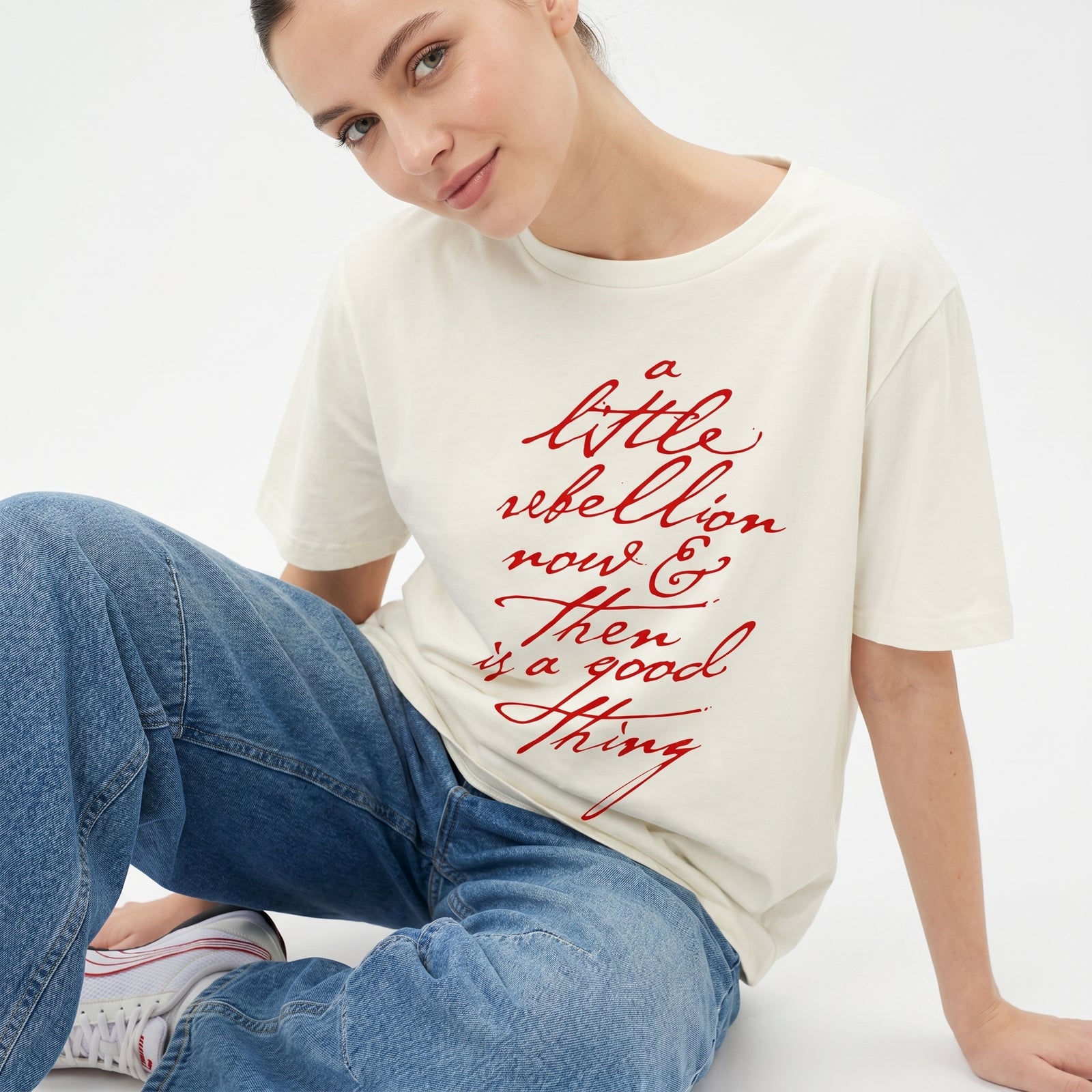 Person wearing a white t-shirt with red text and blue jeans on a white background