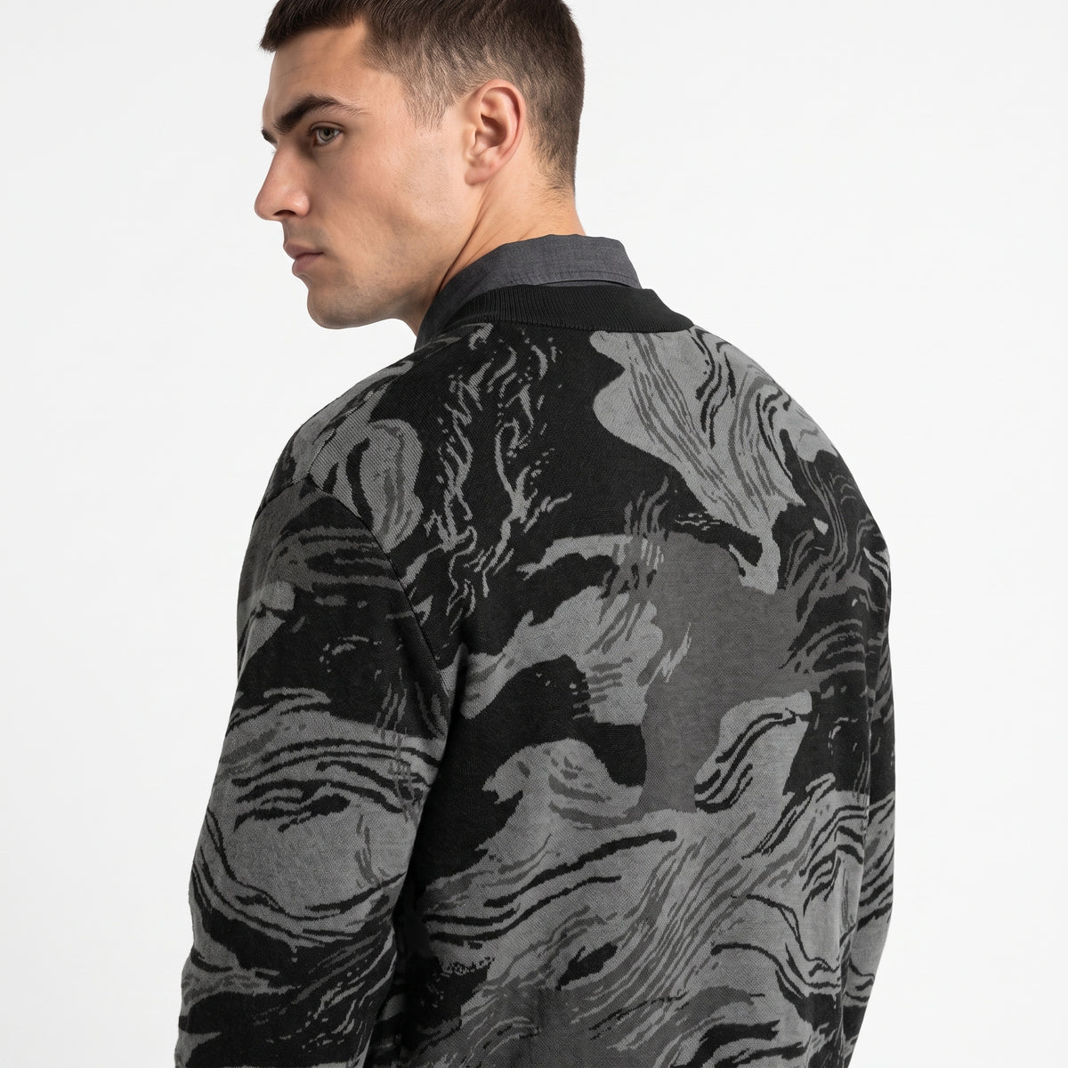 Man wearing a black and gray patterned shirt on a white background