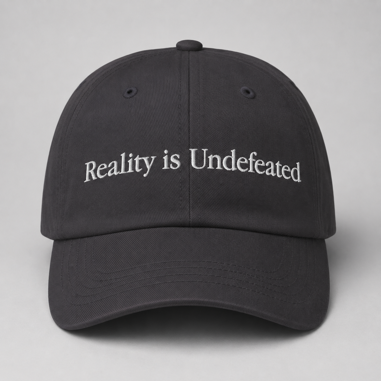 Black cap with 'Reality is Undefeated' text on a gray background