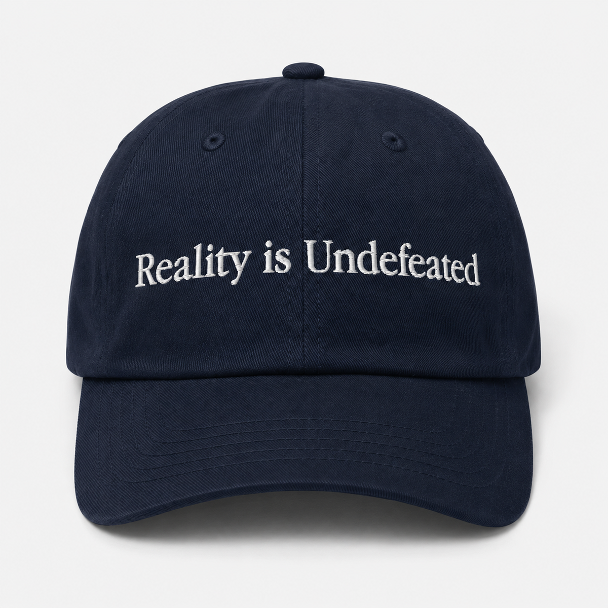 Navy blue cap with 'Reality is Undefeated' text on a white background