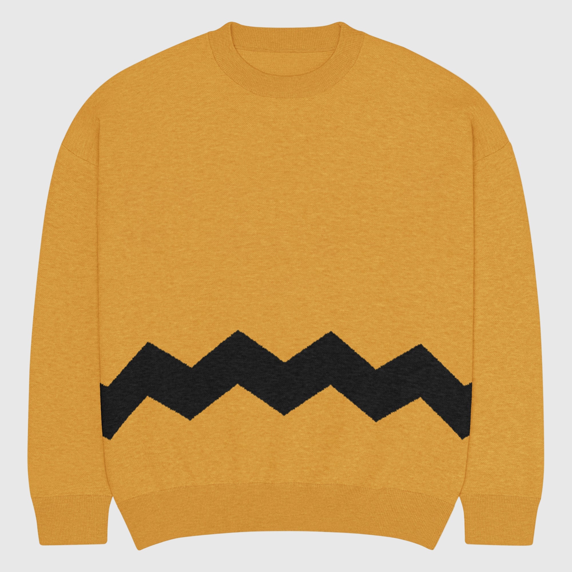 Person wearing a mustard yellow sweater with a black zigzag pattern on a gray background. The Sweater is called the Chuck Brown Relaxed Fit knitted Crew Neck Sweater.