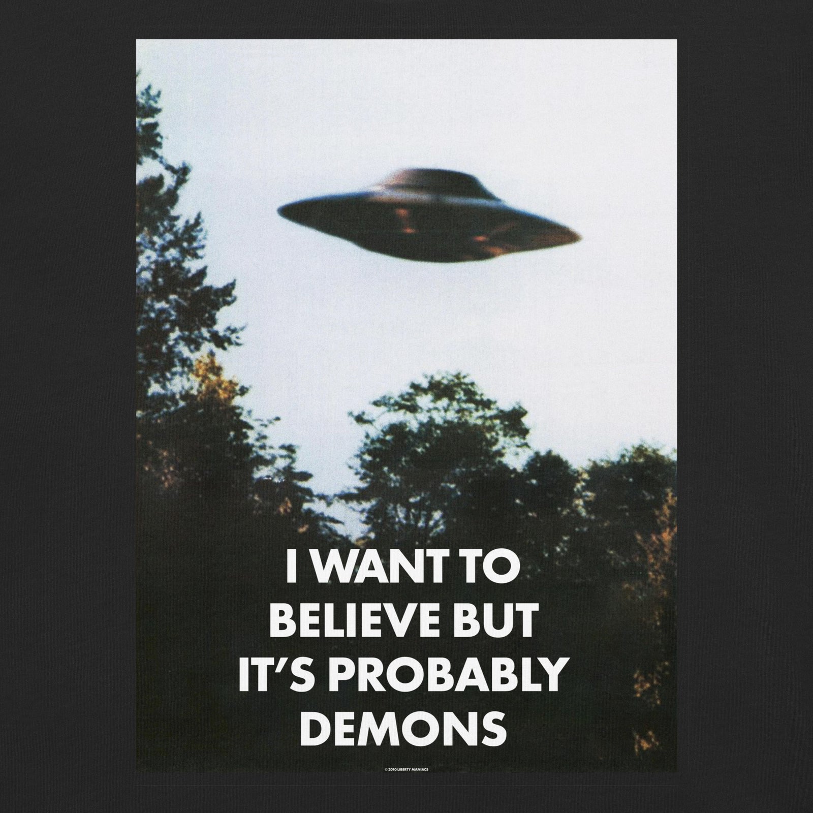 Black t-shirt with a graphic of a UFO and text 'I want to believe but it's probably demons' on a white background.