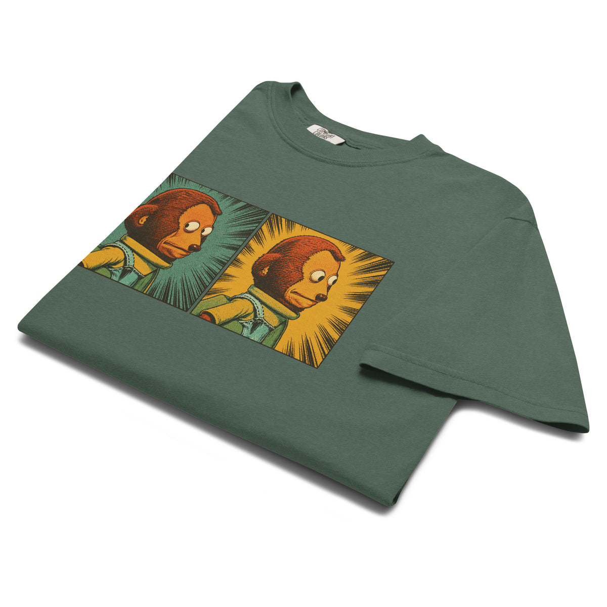 Folded flat lay image of a sage green garment-dyed graphic T-shirt featuring a two-panel vintage comic-style monkey making an awkward side-eye expression.