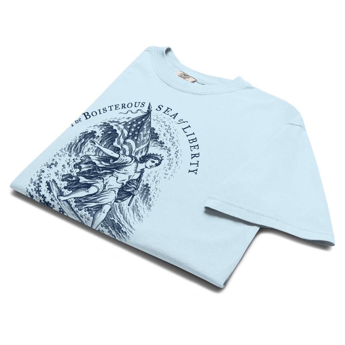 Folded Chambray Sea of Liberty T-shirt, angled close-up showing navy Jefferson quote and surfing Liberty print