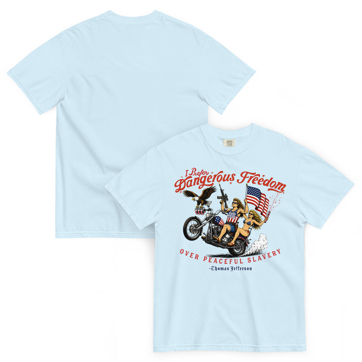A light blue short-sleeve t-shirt shown from both front and back. The front featuring a retro-style illustration of a man and women on a motorcycle with American flags, an eagle, and fireworks. Red text above reads 'I Prefer Dangerous Freedom' and text below reads 'OVER PEACEFUL SLAVERY -Thomas Jefferson'. By Liberty Maniacs