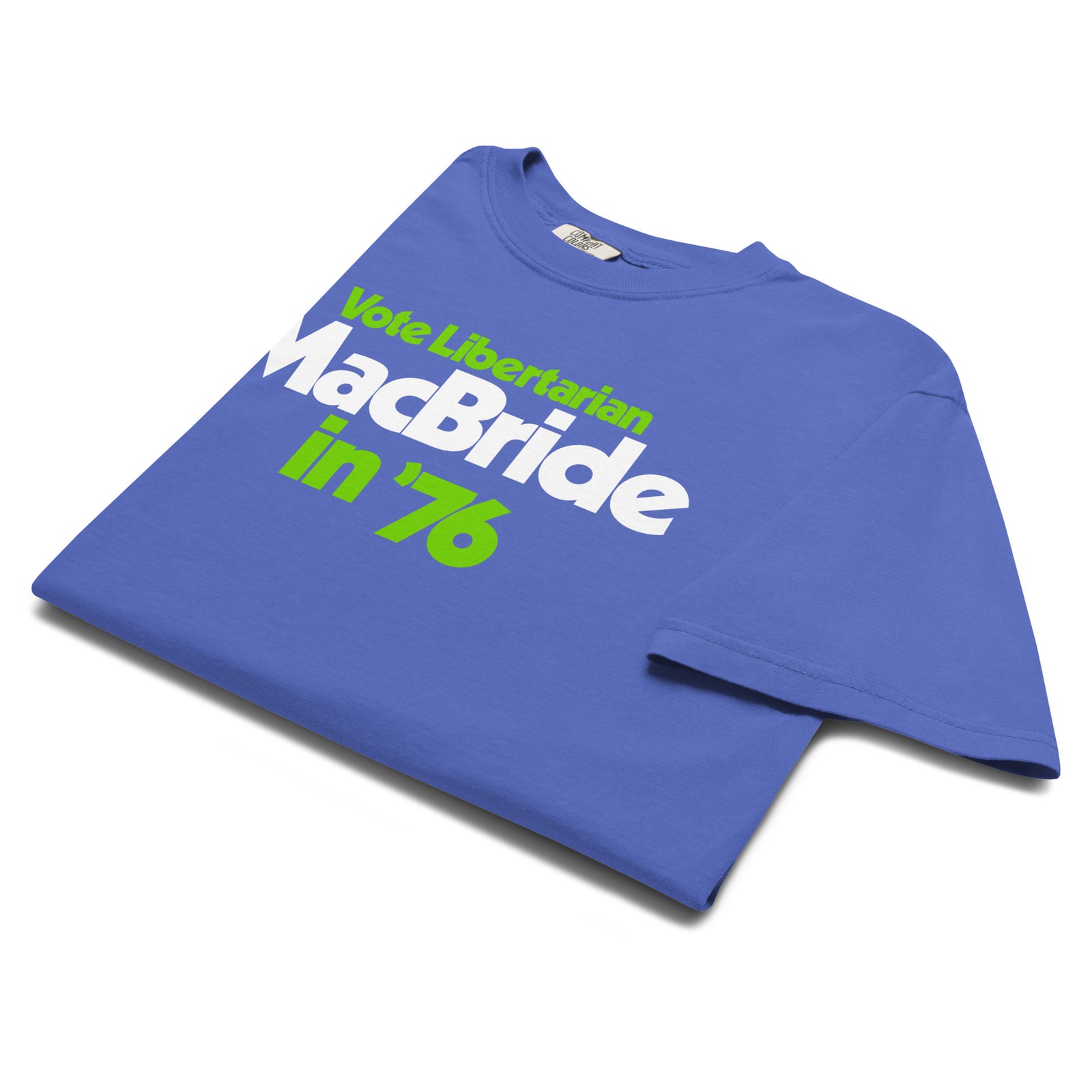 A folded royal blue t-shirt with a graphic print reading 'Vote Libertarian MacBride in '76' in white and lime green text, displayed on a clean white background.